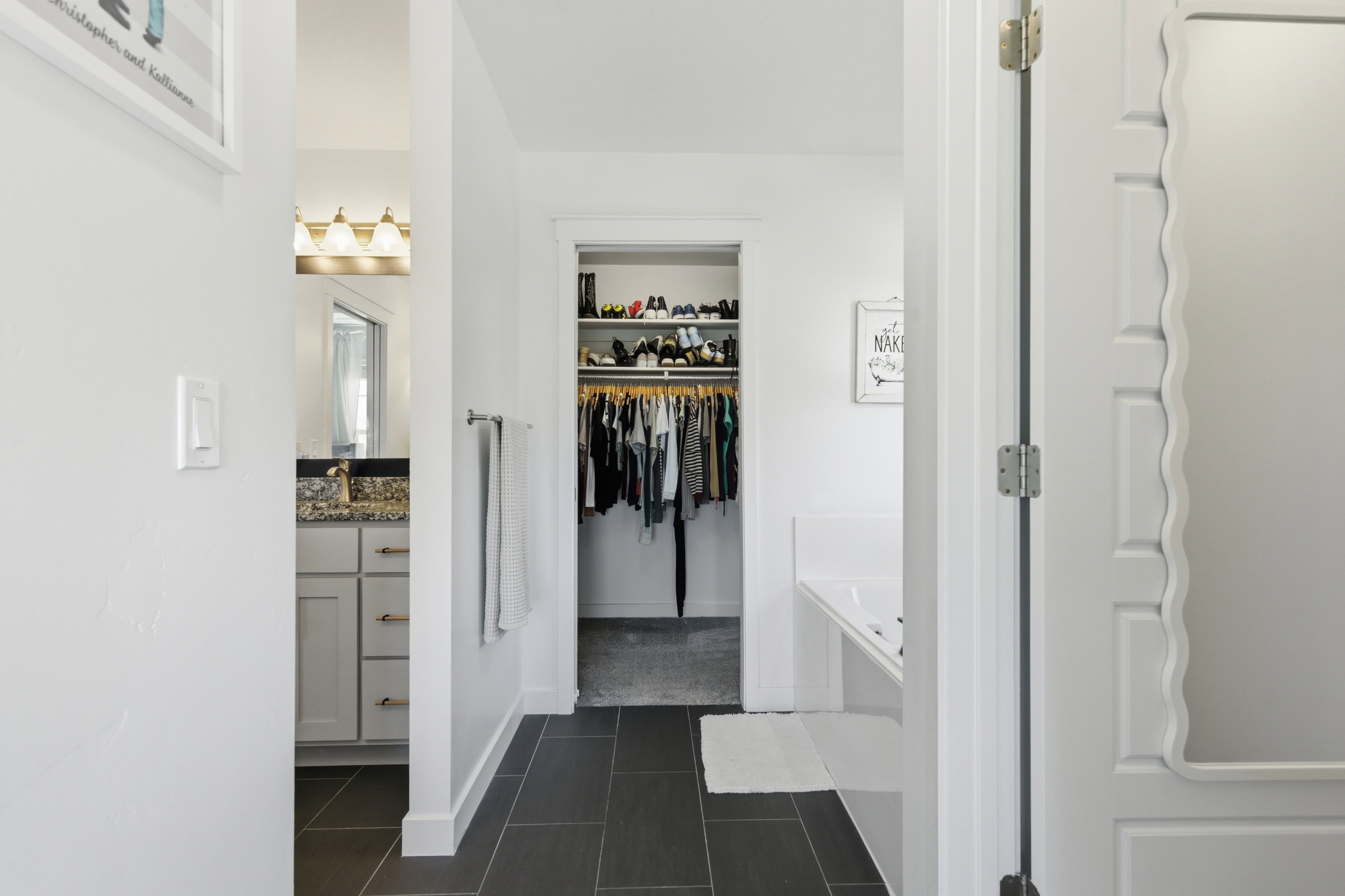 Bathroom featuring dark tile flooring, a built-in bathtub, and a separate vanity with a light-colored countertop