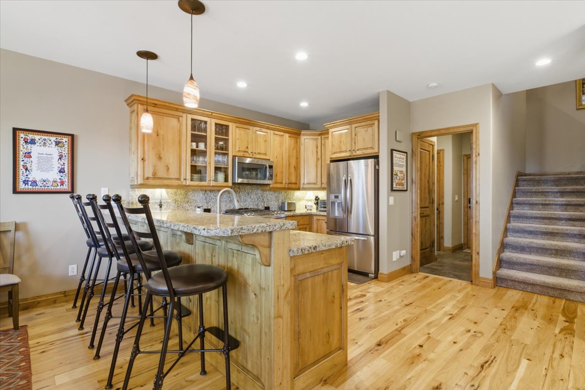 Kitchen featuring wood-finish cabinetry, stainless steel appliances, and a peninsula with a stone countertop