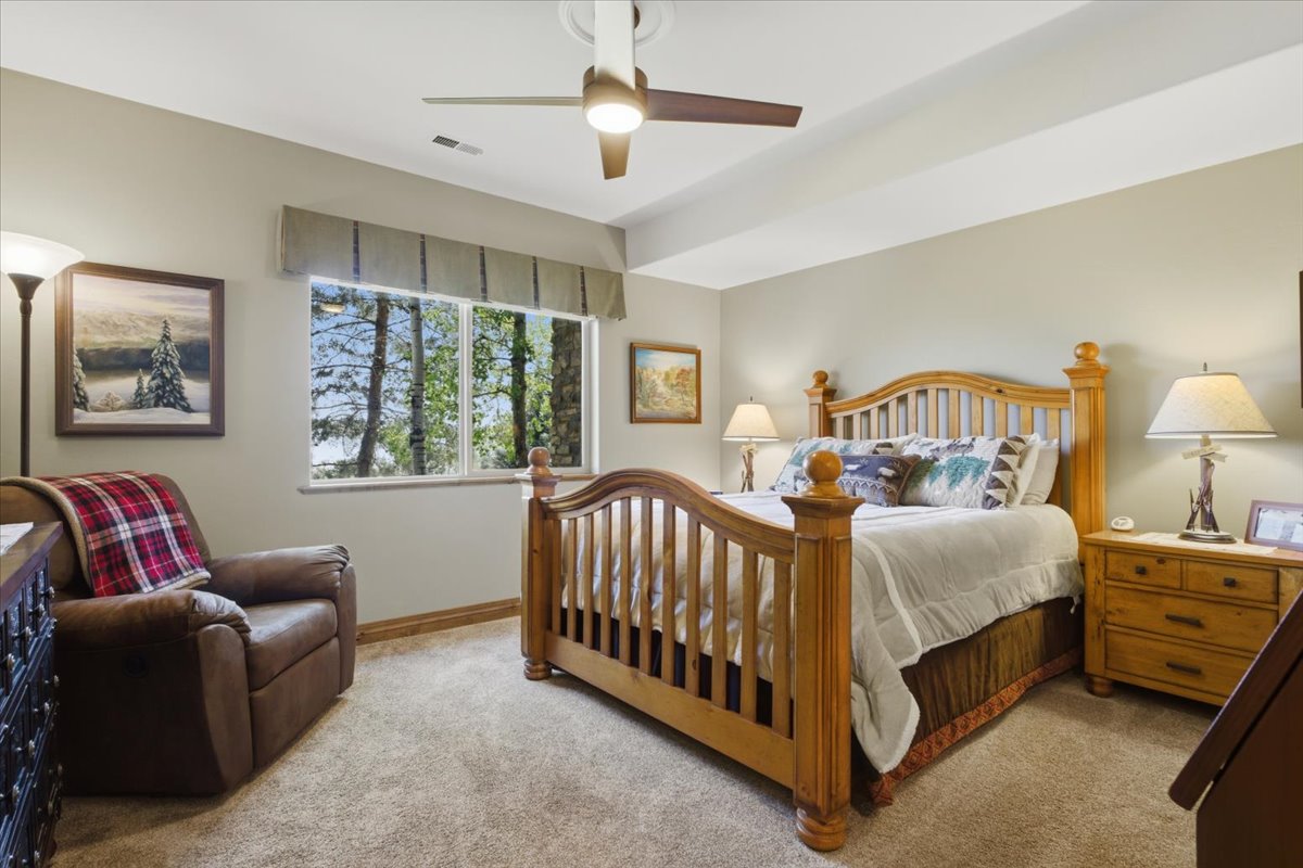 Bedroom featuring a ceiling fan, a window with exterior tree scenery, light-colored carpeting, and light beige wall paint