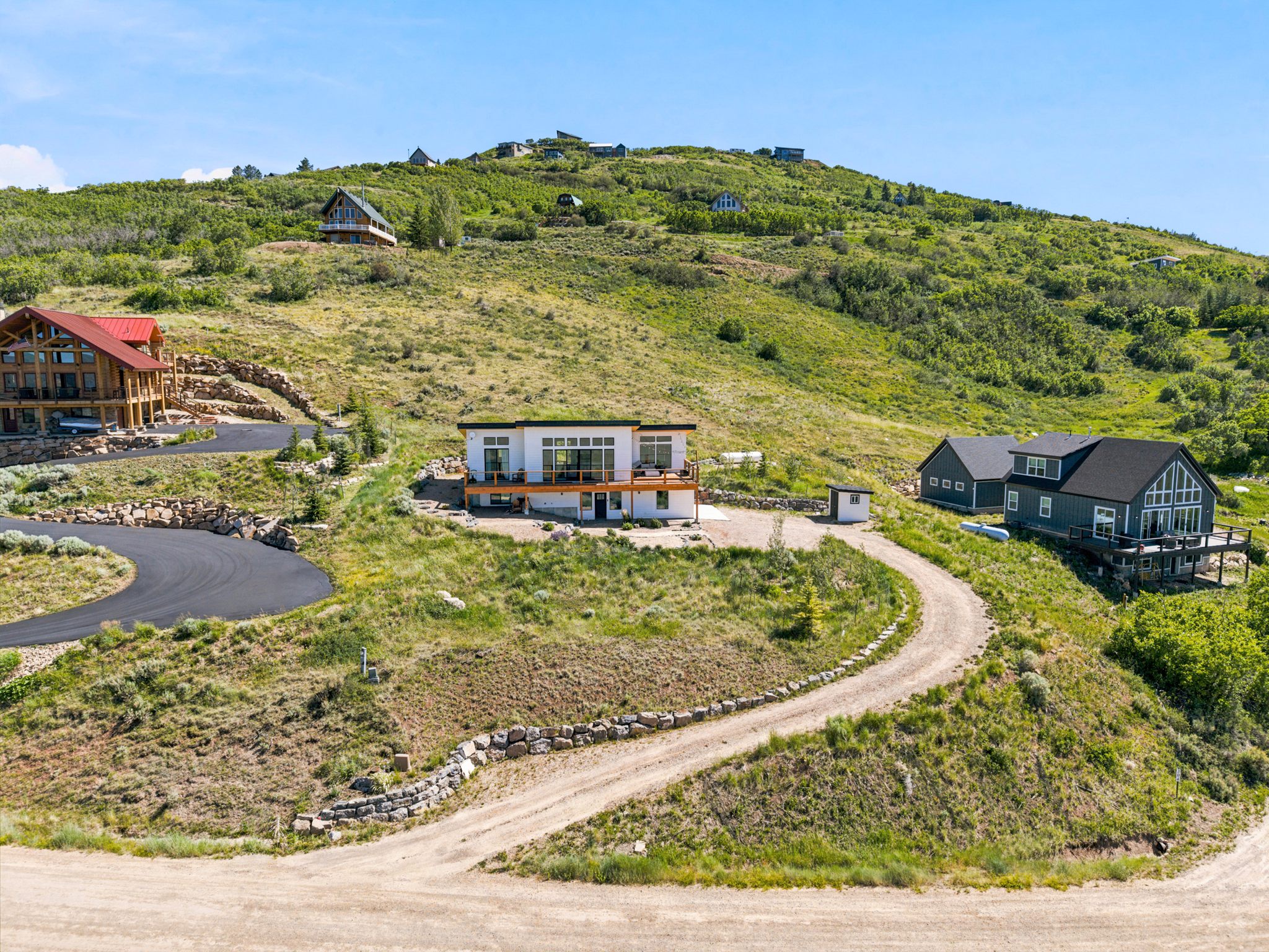 Modern home with multi-level decks and an expansive glass facade, set into a verdant hillside
