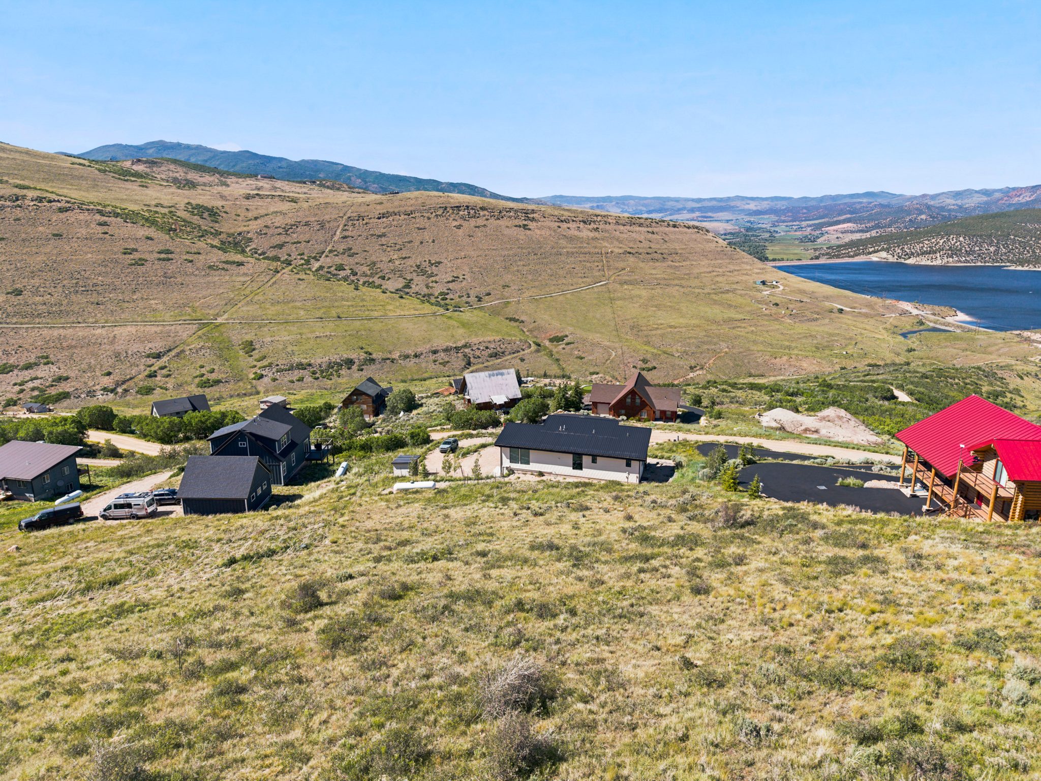 Expansive hillside property featuring a modern residence with a dark roof, surrounded by natural landscaping