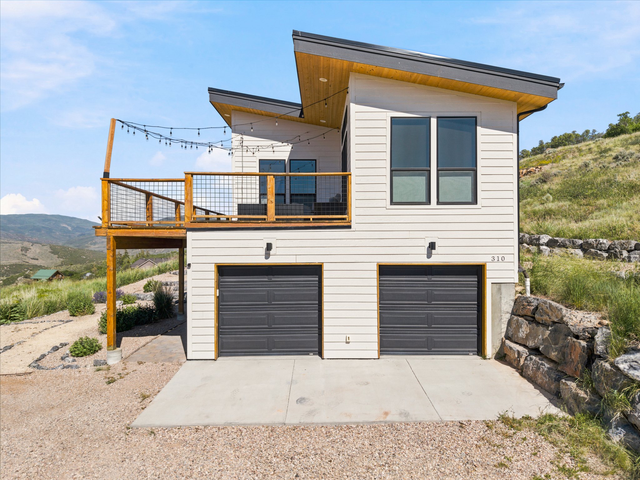 Modern architectural design featuring white horizontal siding and a dark gray garage door