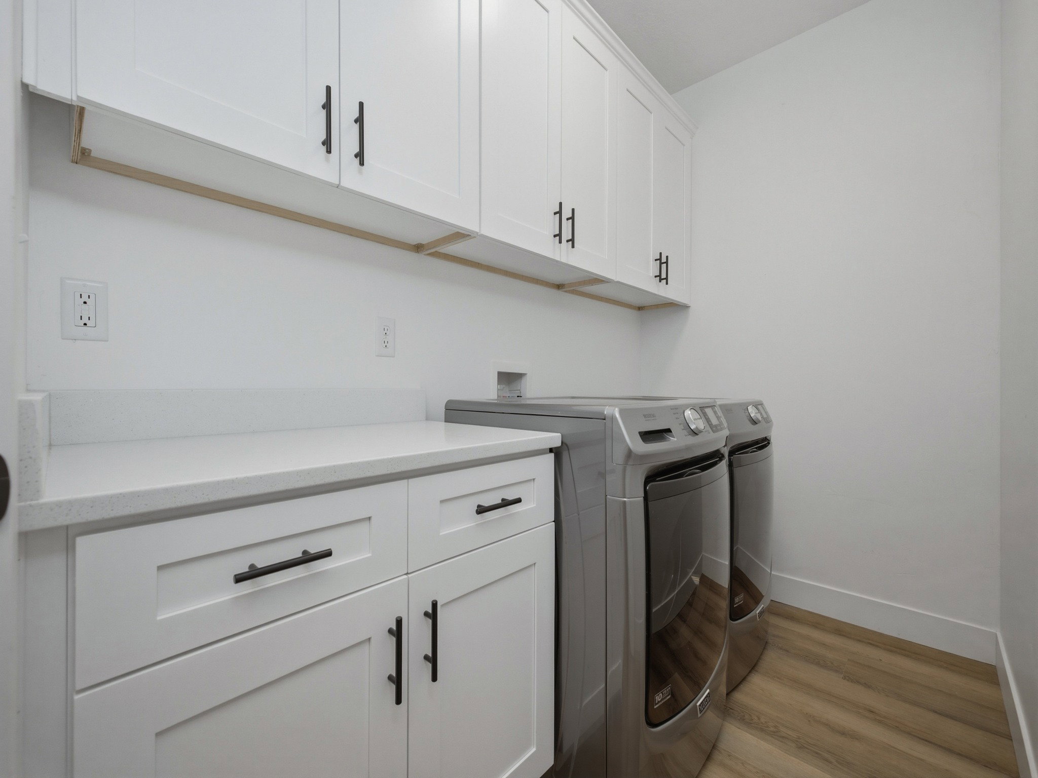 Laundry area featuring white cabinetry with matte black hardware
