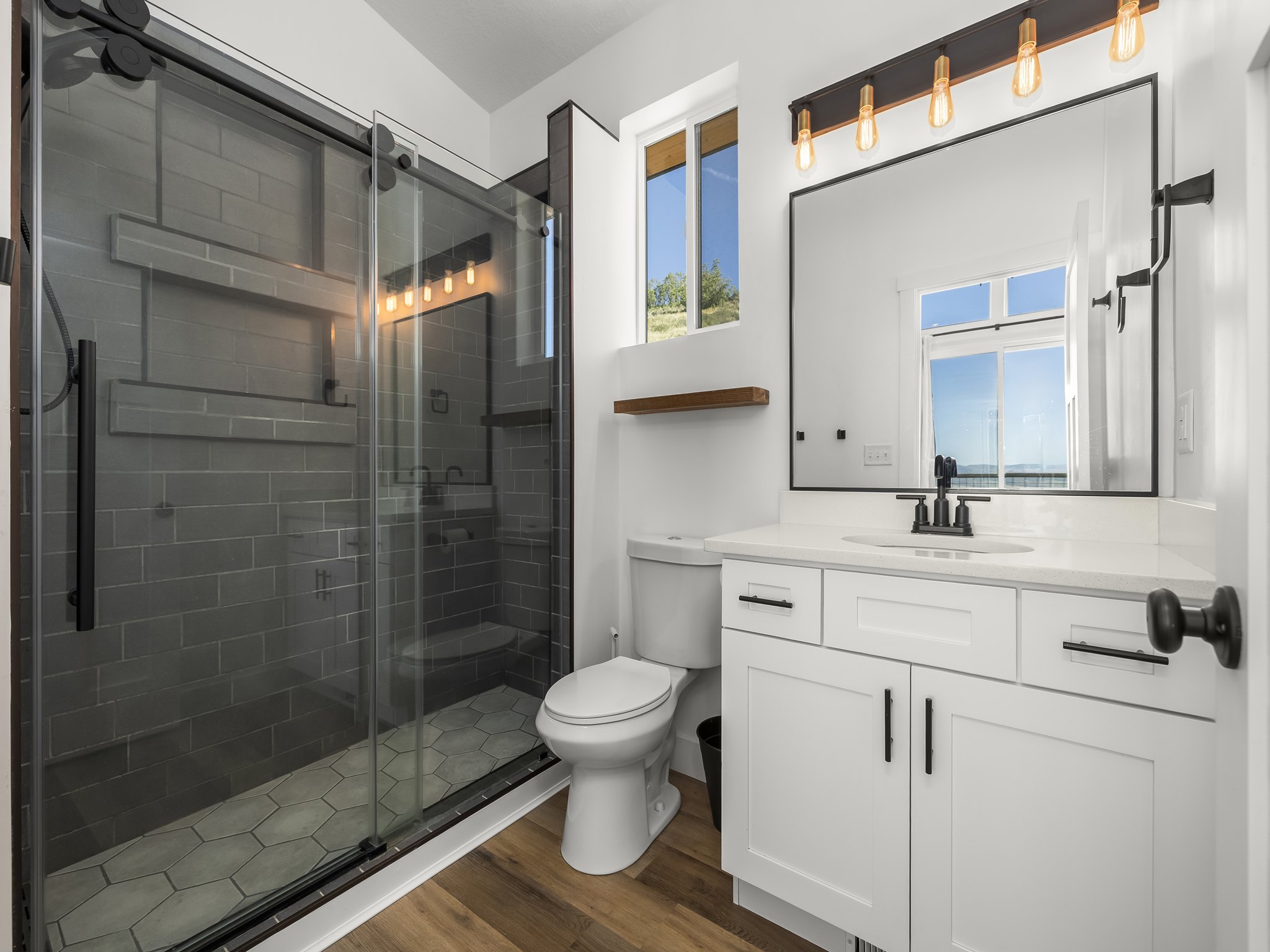 Modern bathroom featuring a glass-enclosed shower with subway tile surround and hexagonal floor tiles