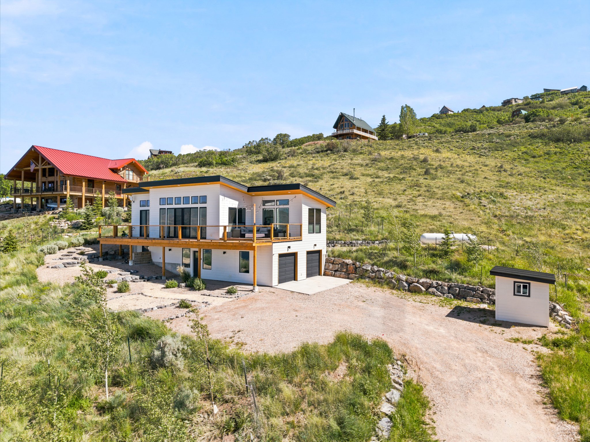 Modern exterior with a flat roofline, expansive upper-level deck, multiple large windows, and an attached two-car garage