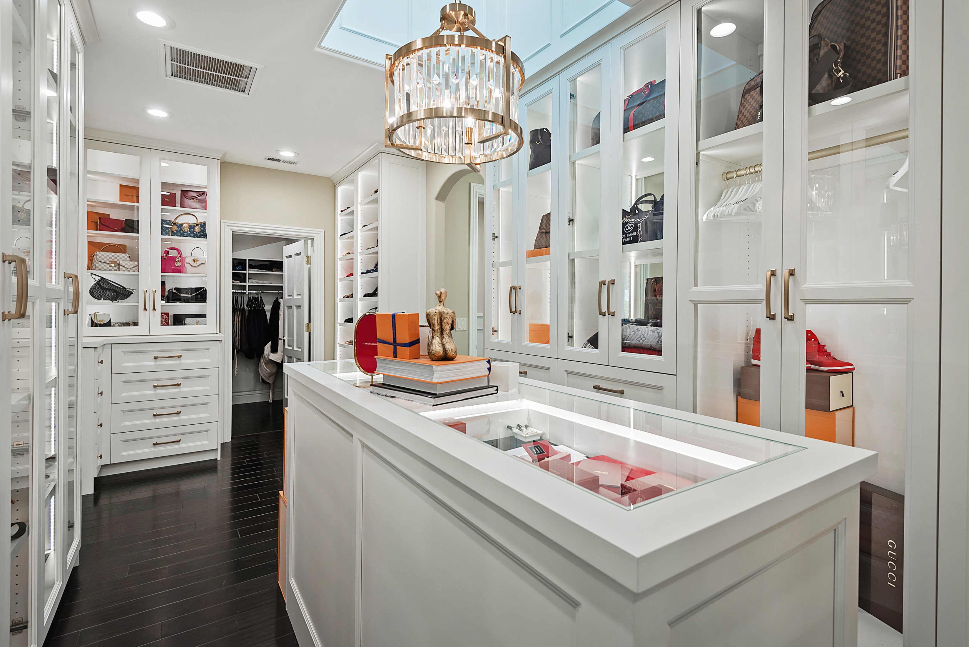 Custom closet featuring dark wood-finish flooring and extensive white cabinetry