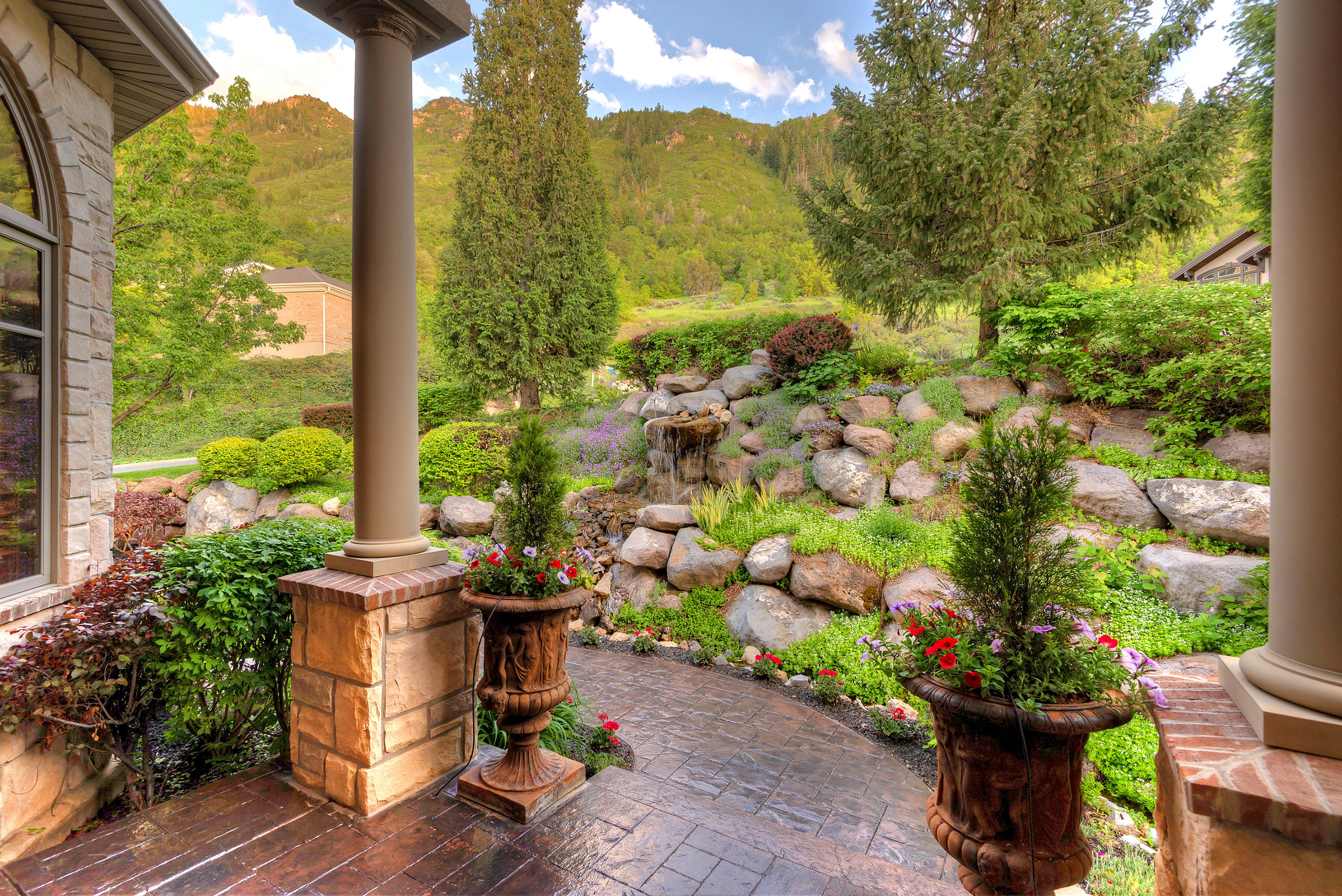 Front patio featuring an arched window, stone and brick column base, and a stamped concrete surface