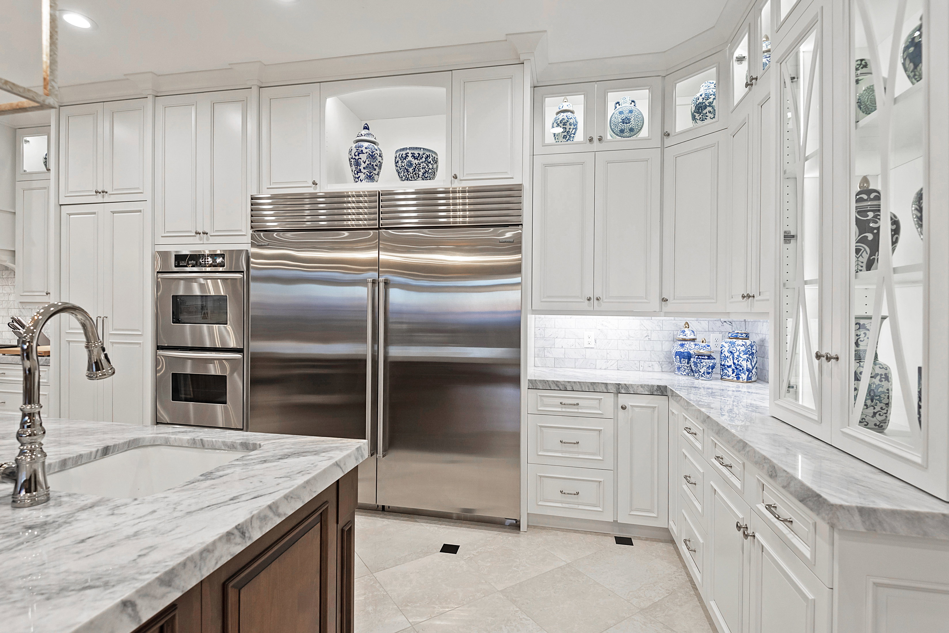 Gourmet kitchen featuring white shaker cabinetry, stainless steel double ovens, integrated refrigerator and freezer, stone countertops, and a subway tile backsplash
