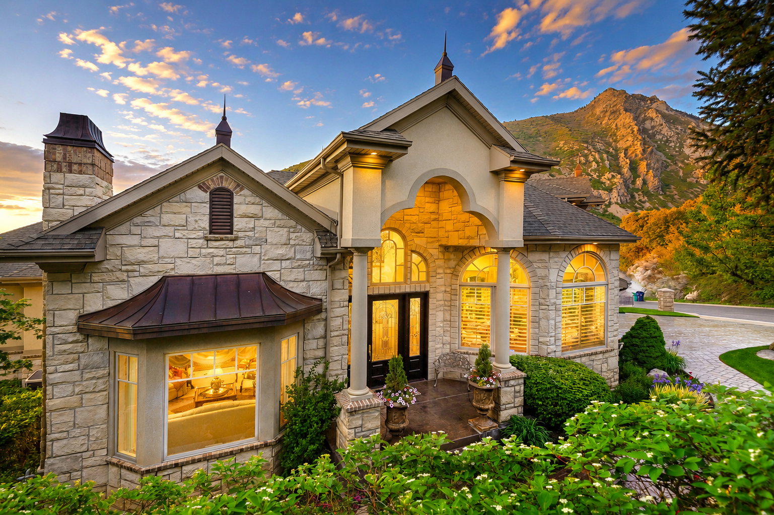 Stone-clad exterior with a prominent arched entry, multiple arched windows, and a bay window featuring a copper roof