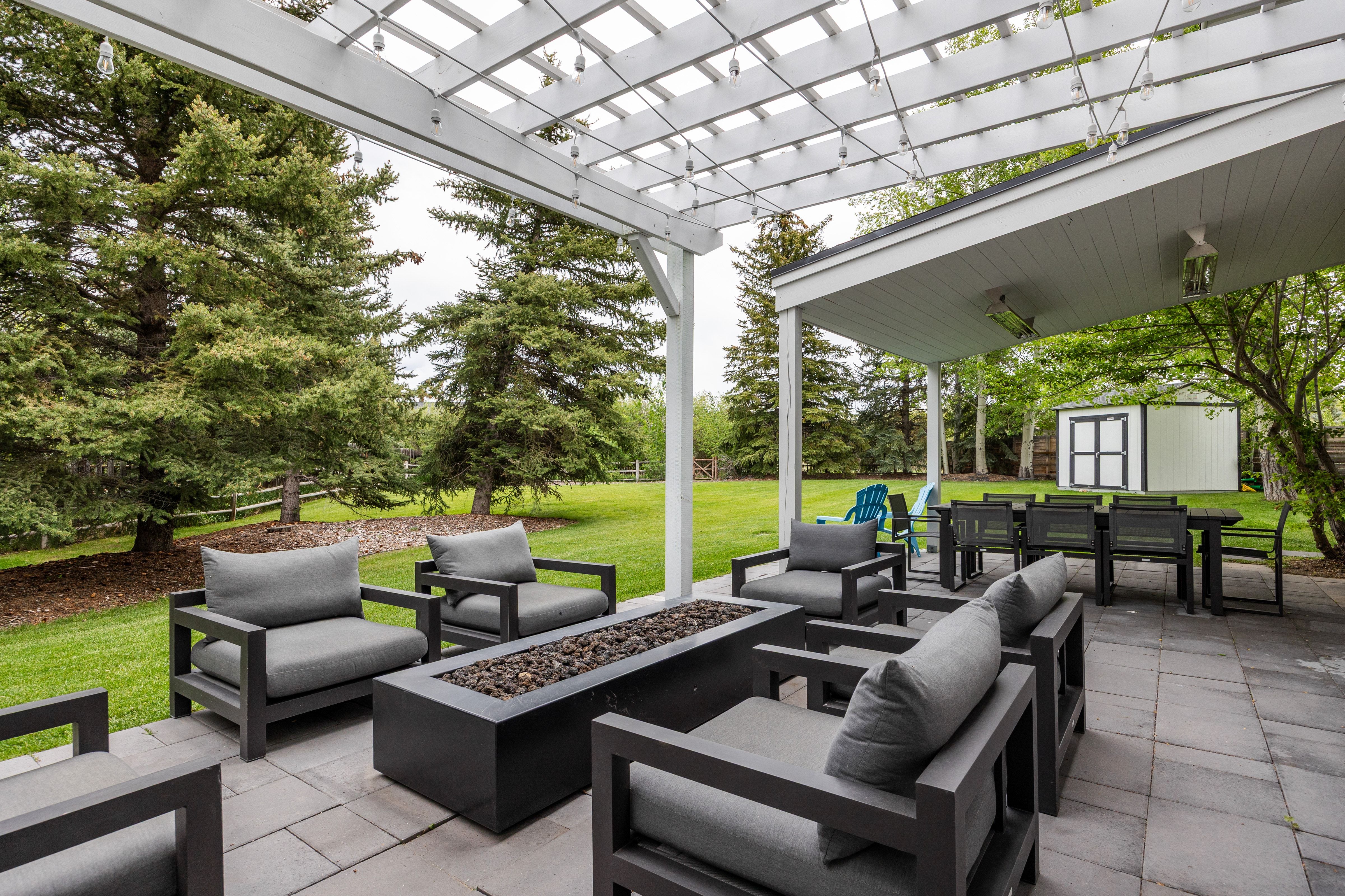Expansive paver patio with a white pergola and string lighting