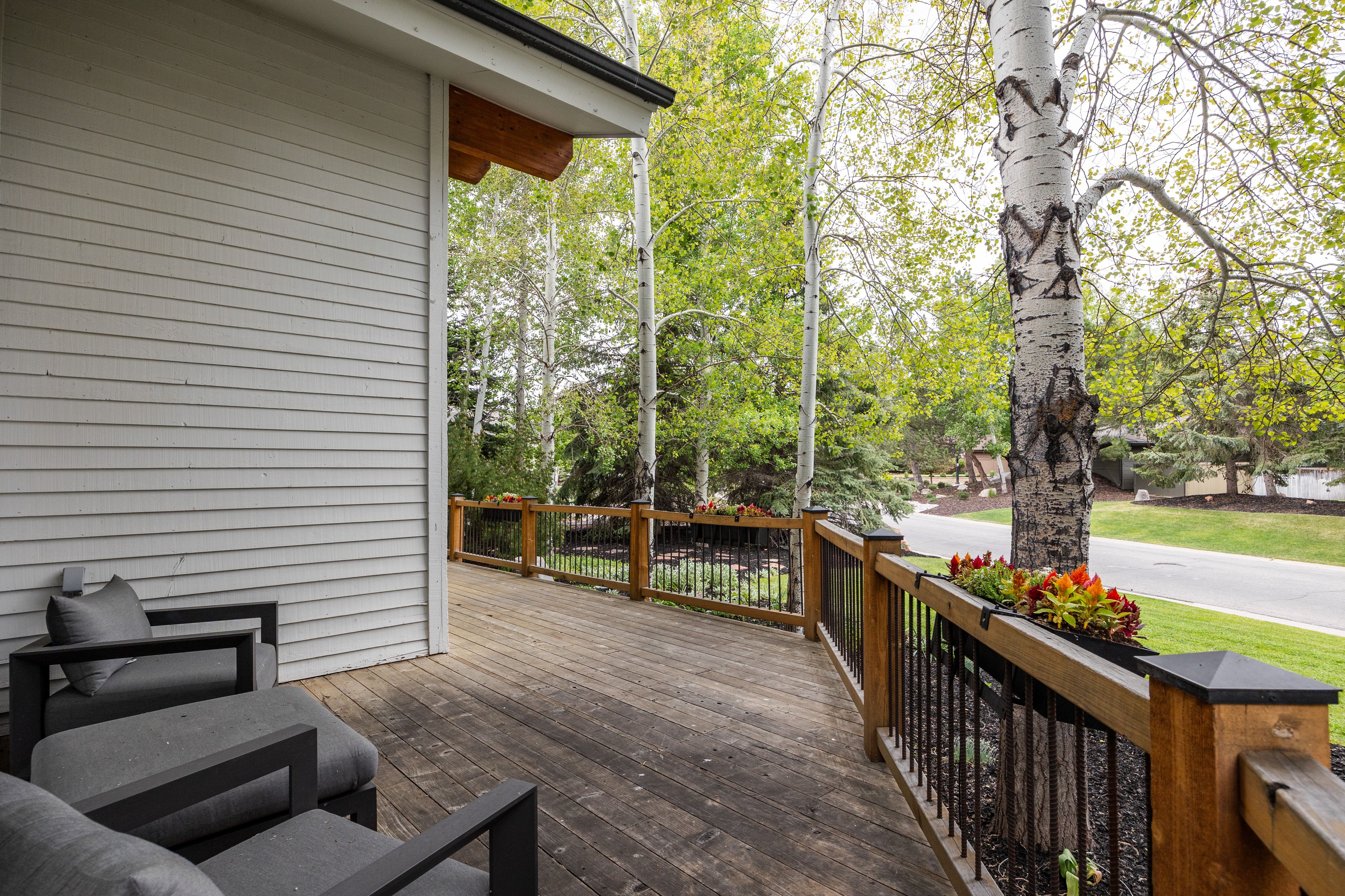 Spacious outdoor deck featuring wood-finish flooring, a horizontal siding exterior, and a wooden railing with black iron balusters