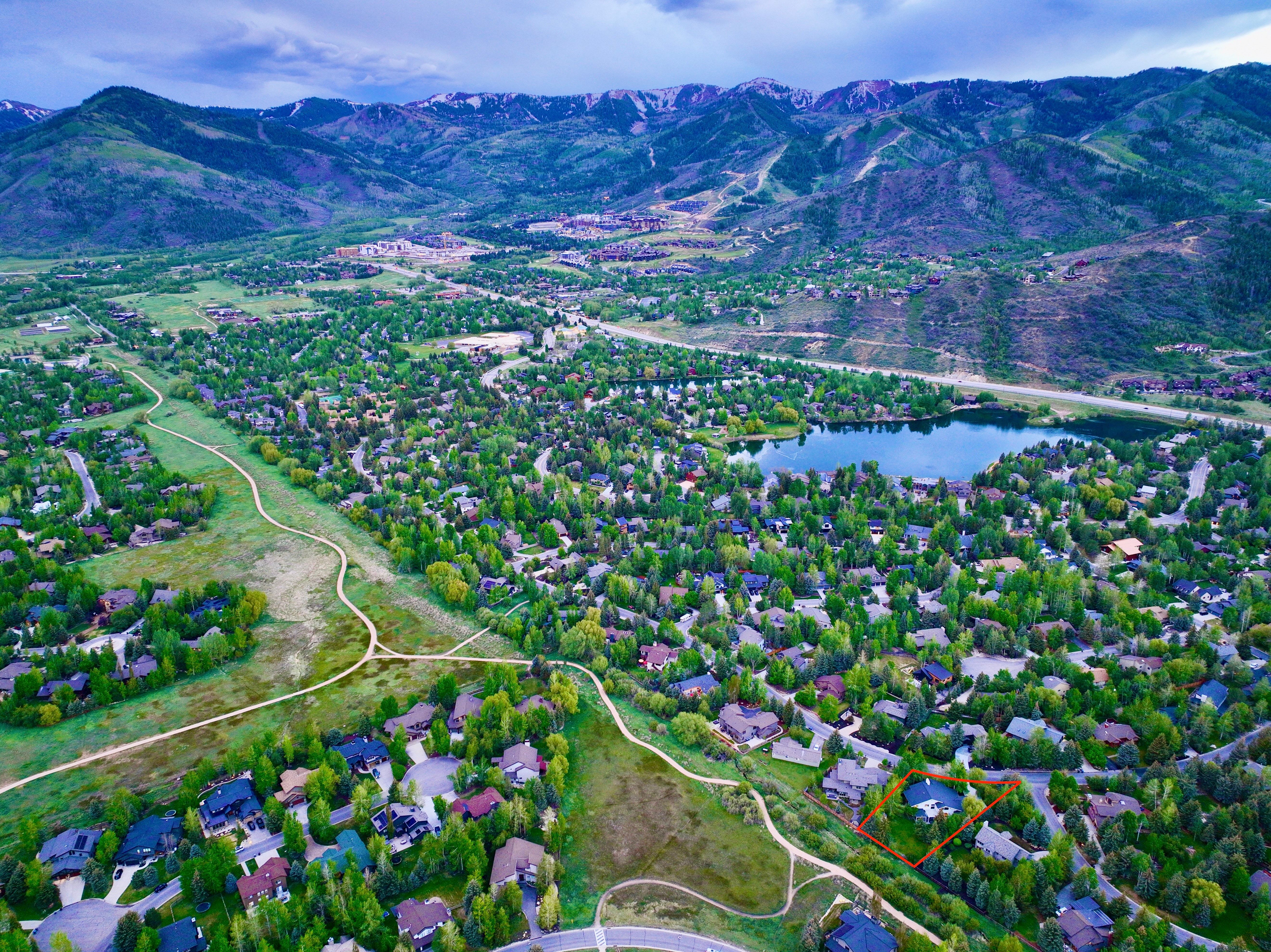 Aerial perspective showcasing a residential community nestled among mature trees and green spaces, featuring a prominent lake