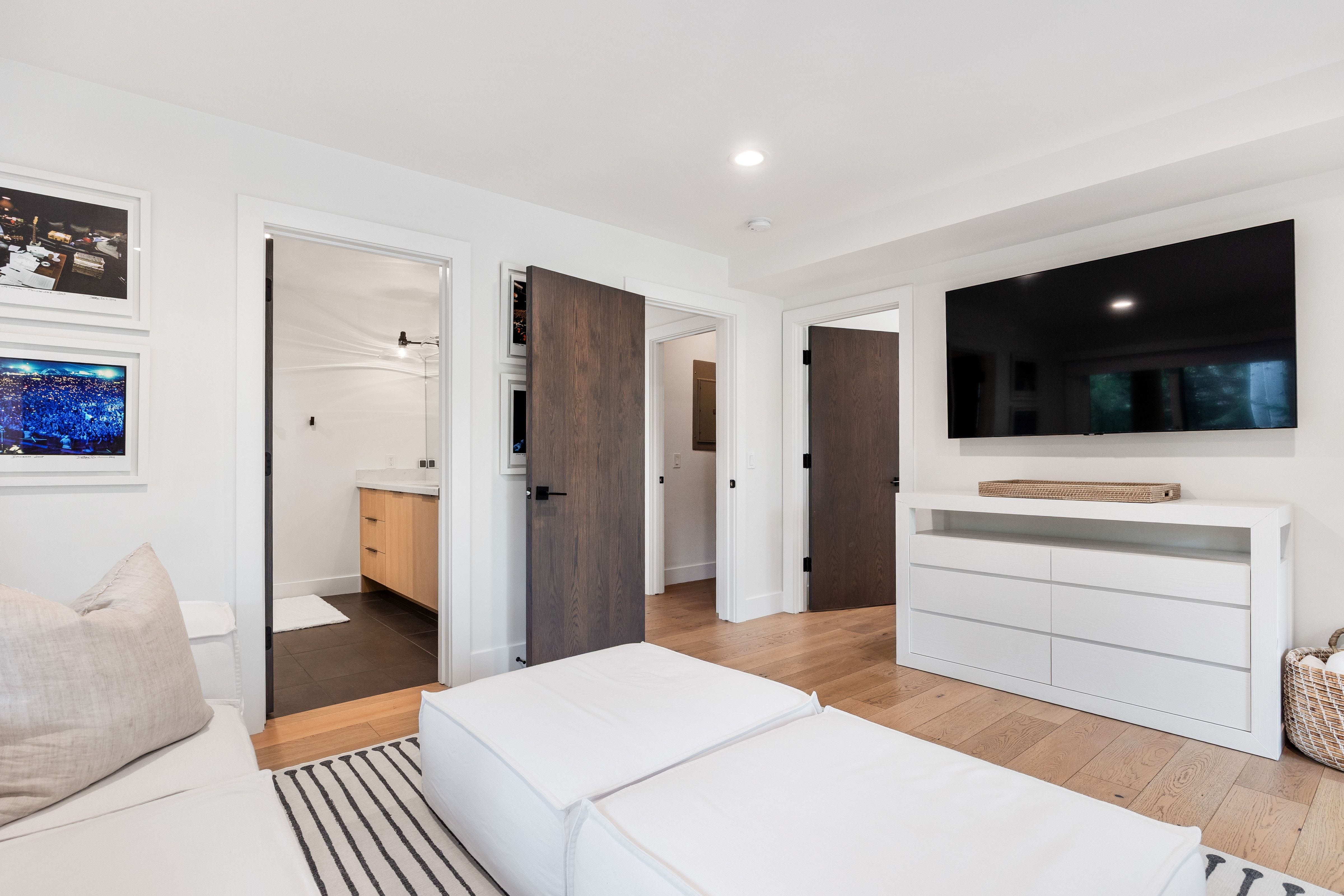 Hardwood flooring and recessed lighting illuminate this bright interior, featuring a built-in entertainment console
