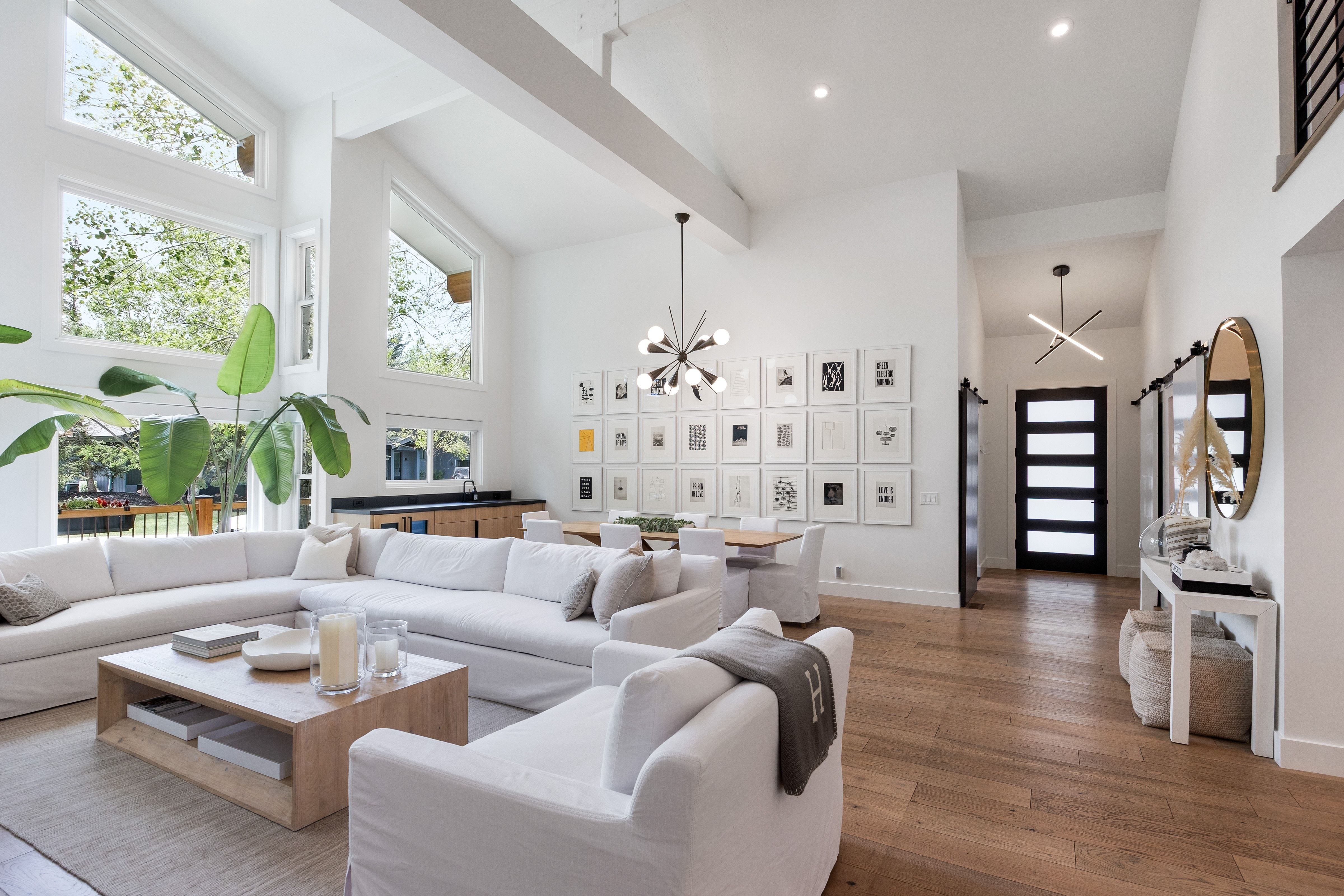 Vaulted ceilings with exposed beams, wood-finish flooring, a built-in wet bar, and a modern chandelier