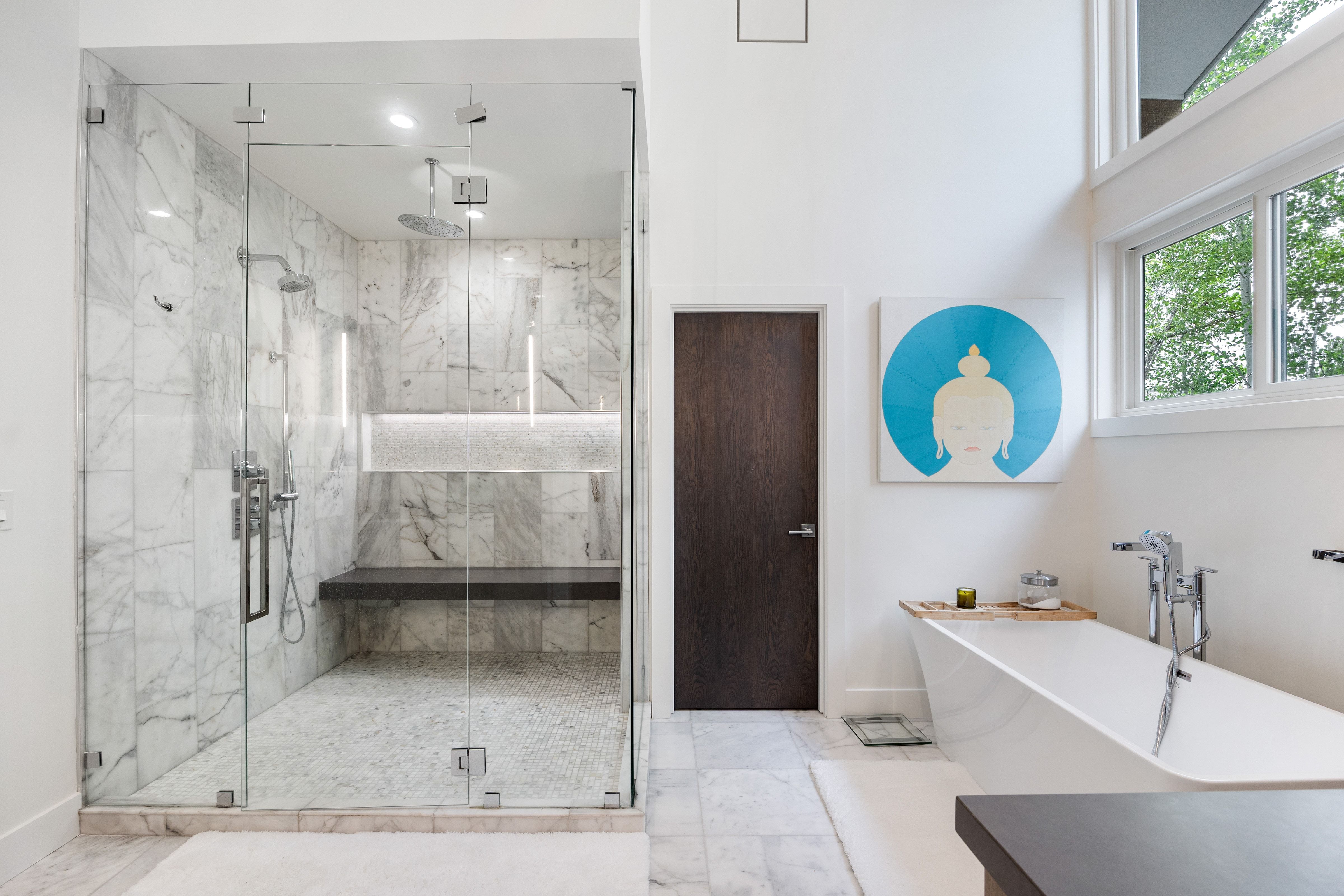 Spacious bathroom featuring a glass-enclosed shower with full-height stone-finish tiling and a built-in bench