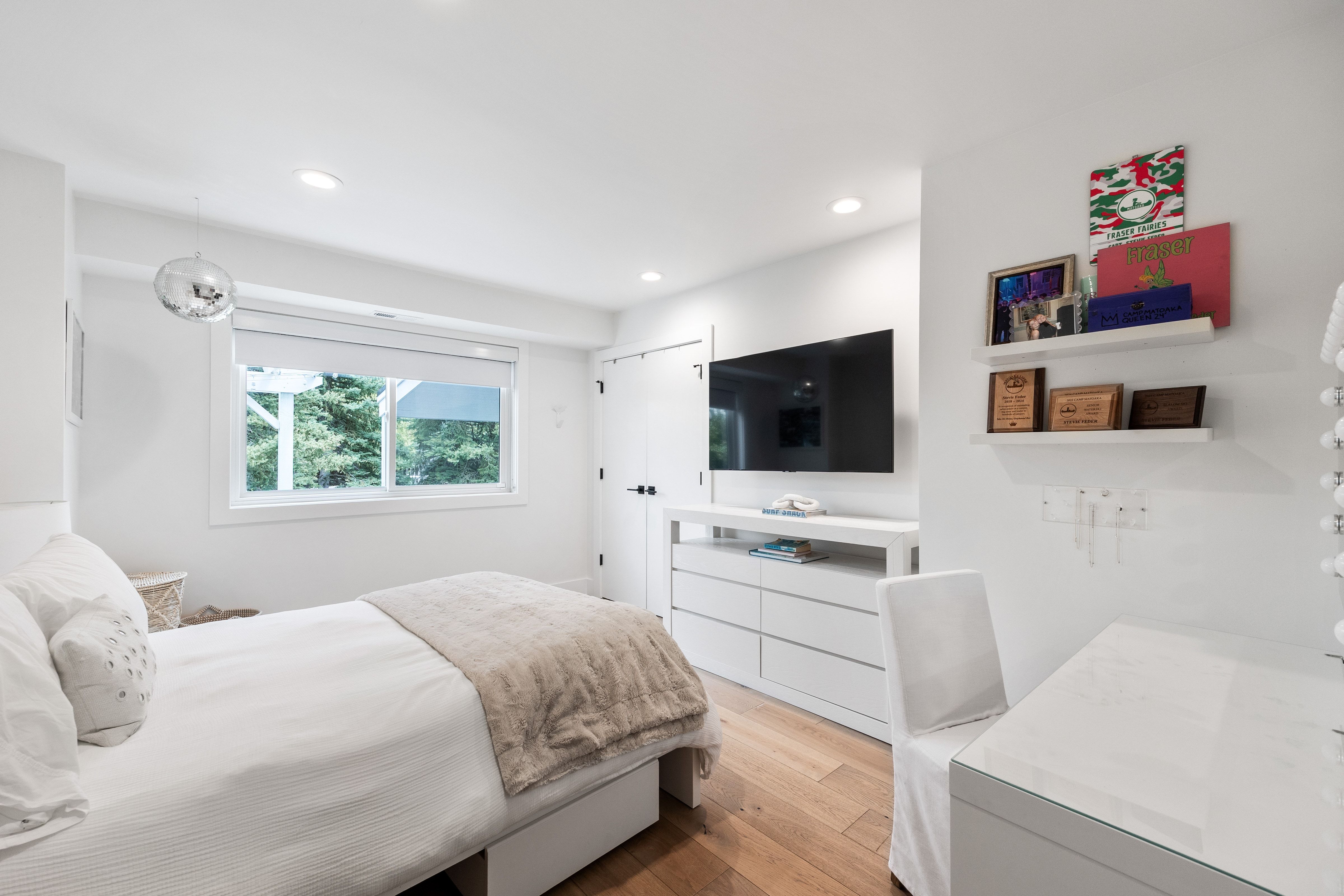 Bright room featuring a large window, recessed lighting, wood-finish flooring, a contemporary floating dresser, and built-in wall shelving