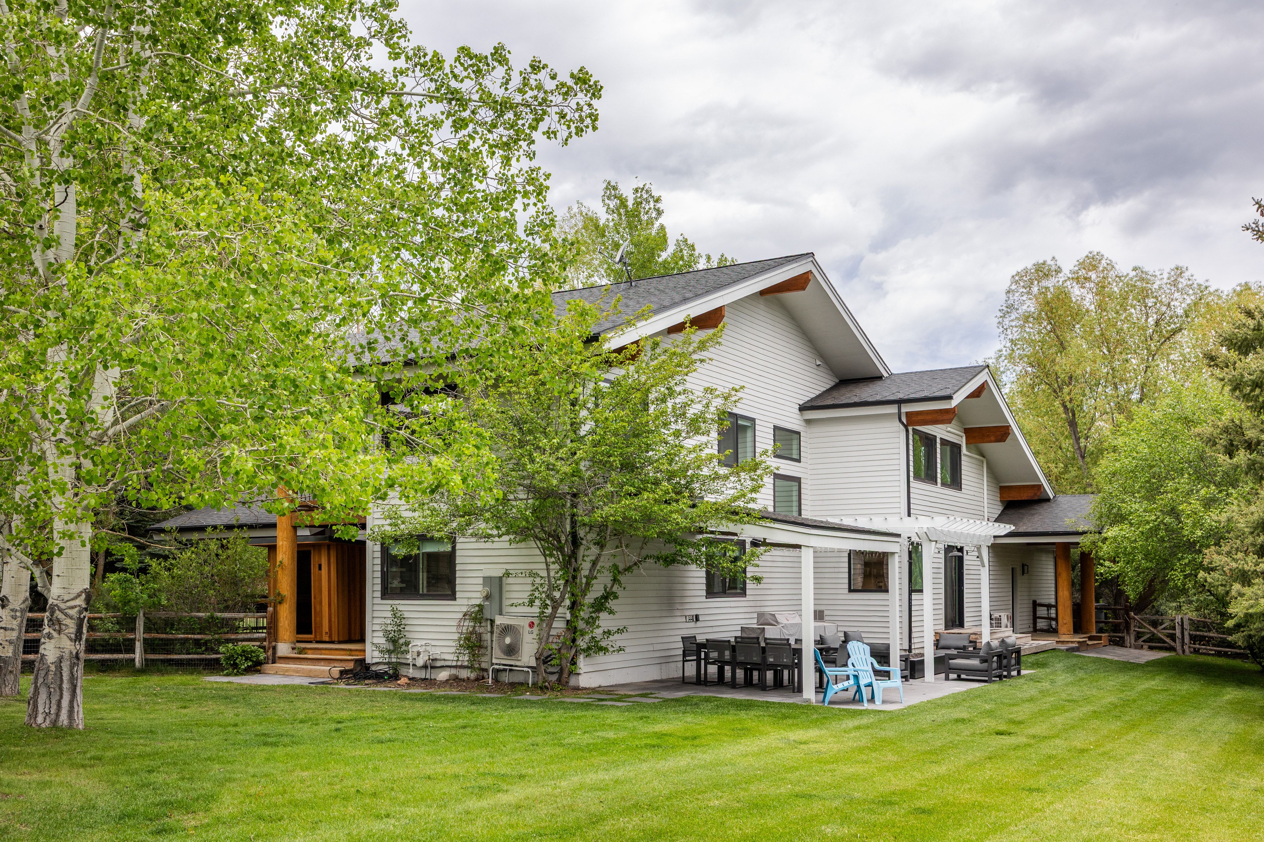 Modern architecture featuring white siding with dark trim, a gabled roofline, and exposed wood structural elements