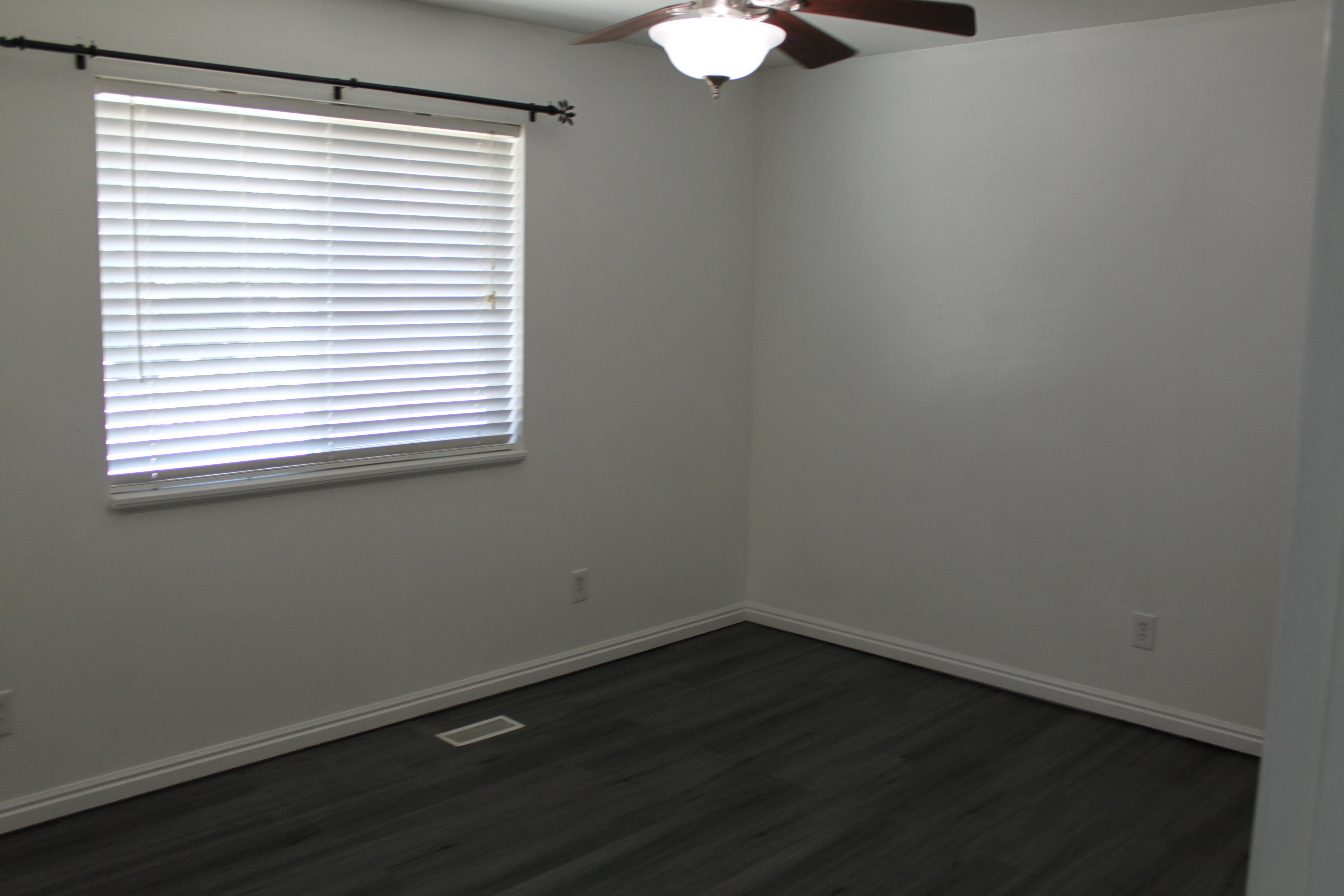 Room featuring dark wood-finish flooring, crisp white baseboards, and neutral wall tones