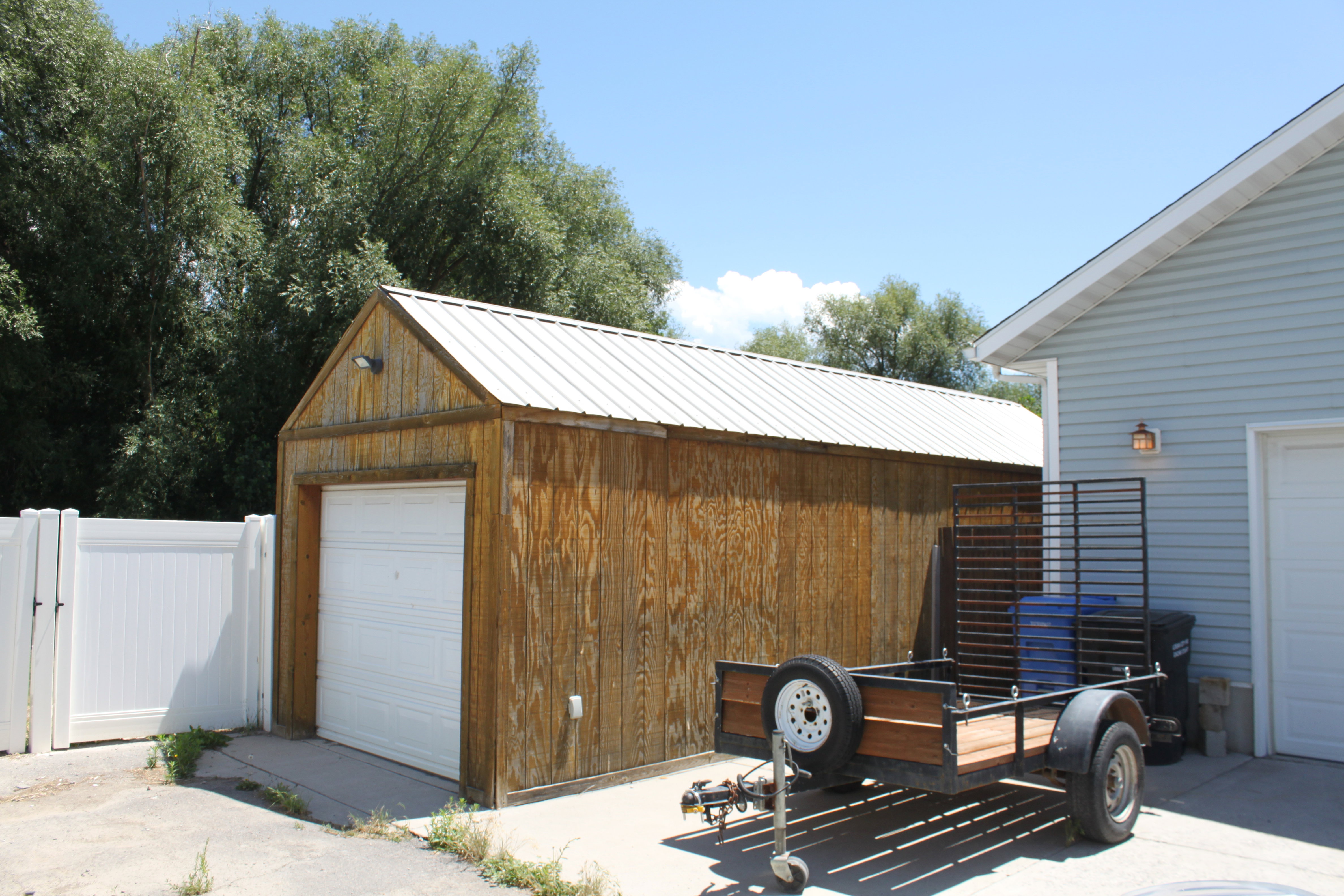 Wood-sided auxiliary structure with a white metal roof and a white garage door
