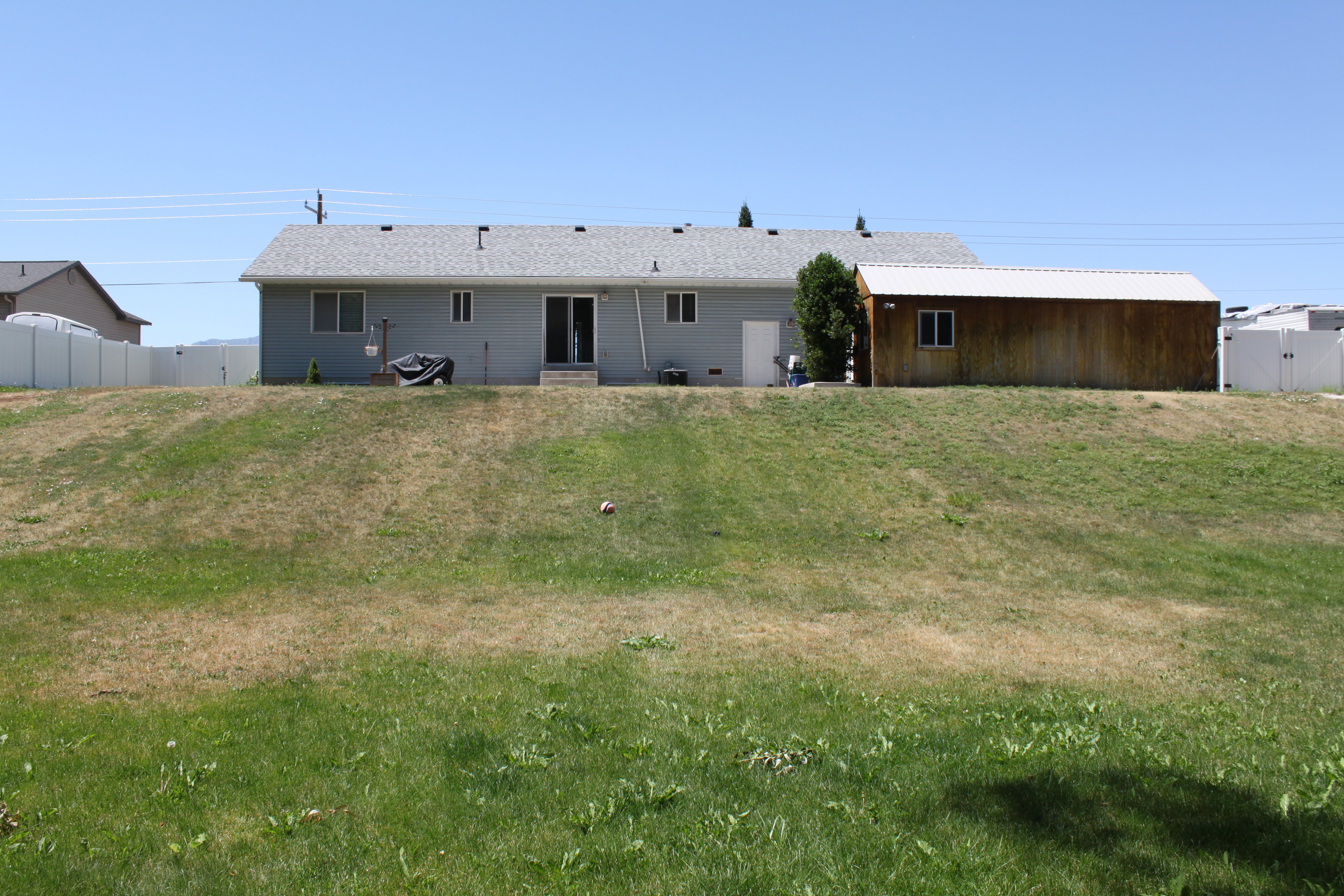 Rear exterior featuring light grey siding and a shingle roof
