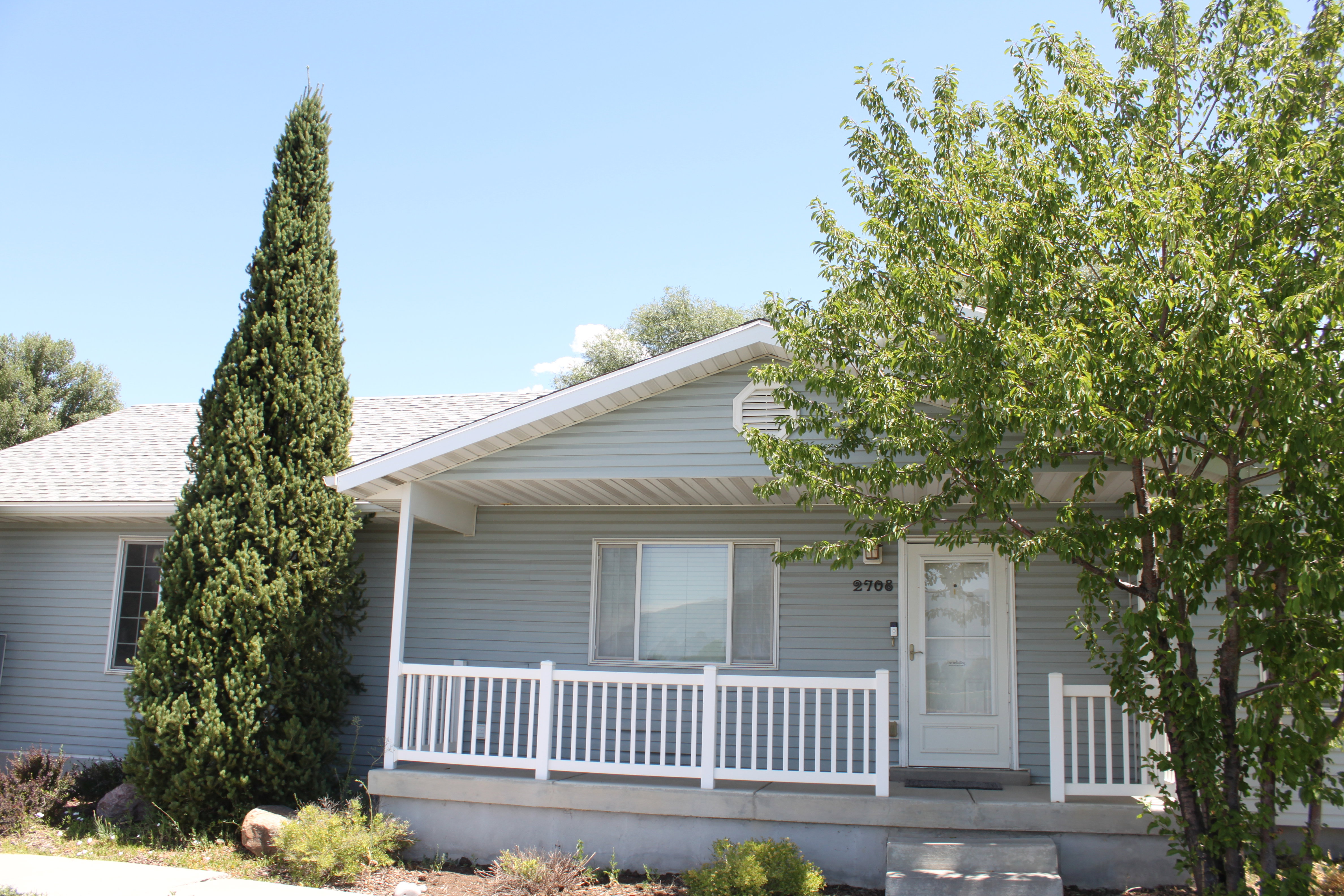 Light blue siding exterior with a covered porch featuring white railing