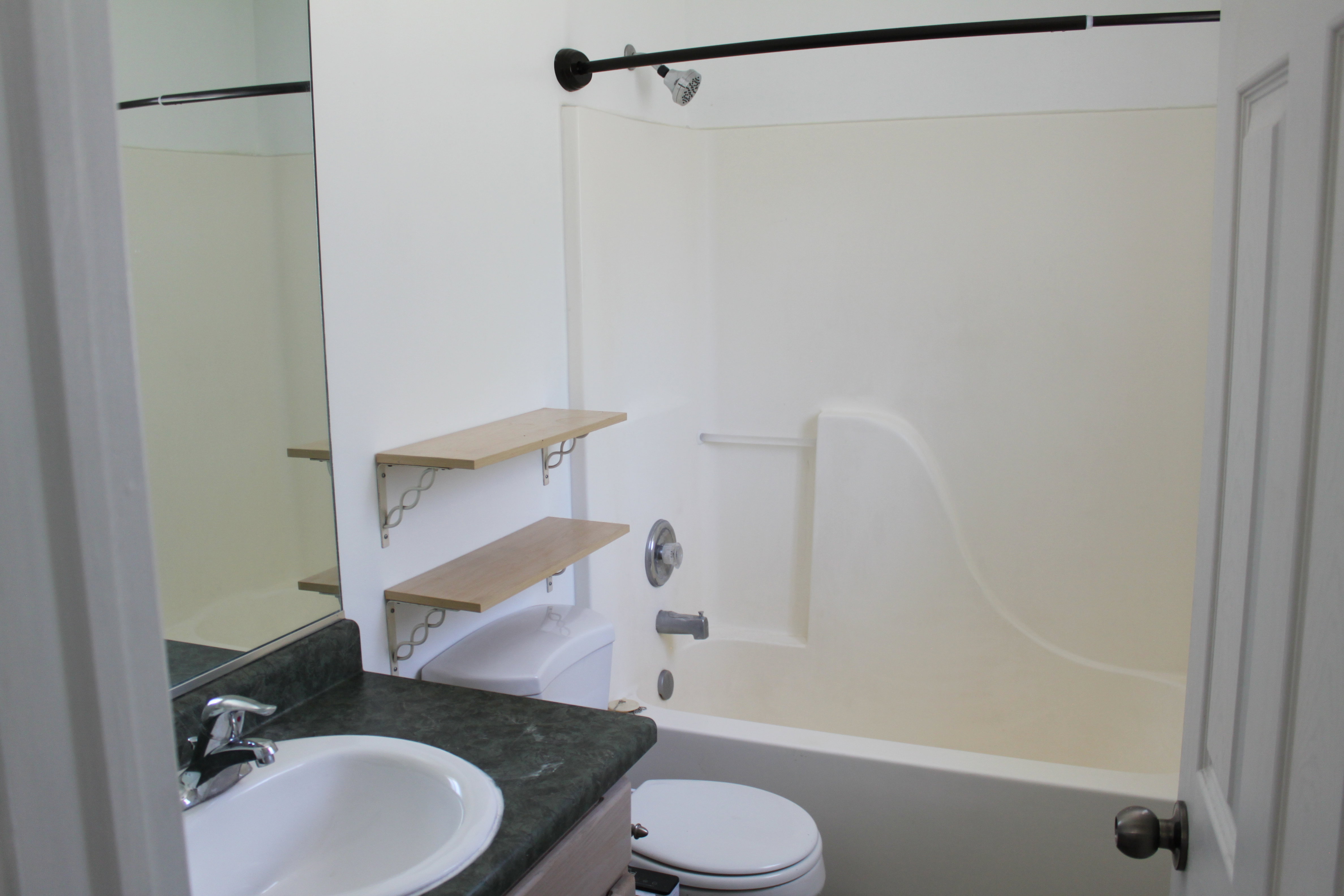 White bathtub with an integrated shower, featuring a black shower rod