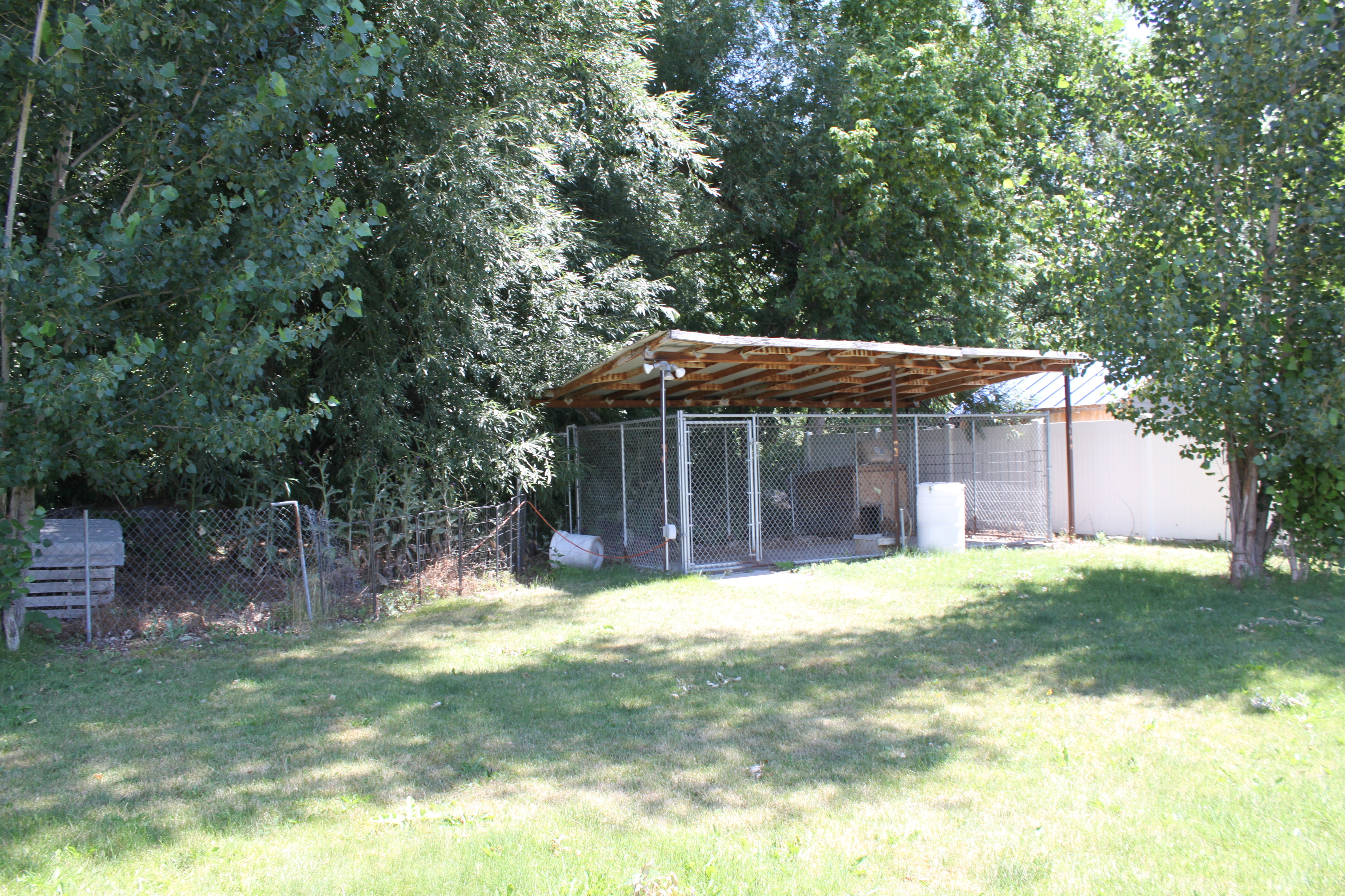 Chain link enclosure with a wood-framed, open-slat roof