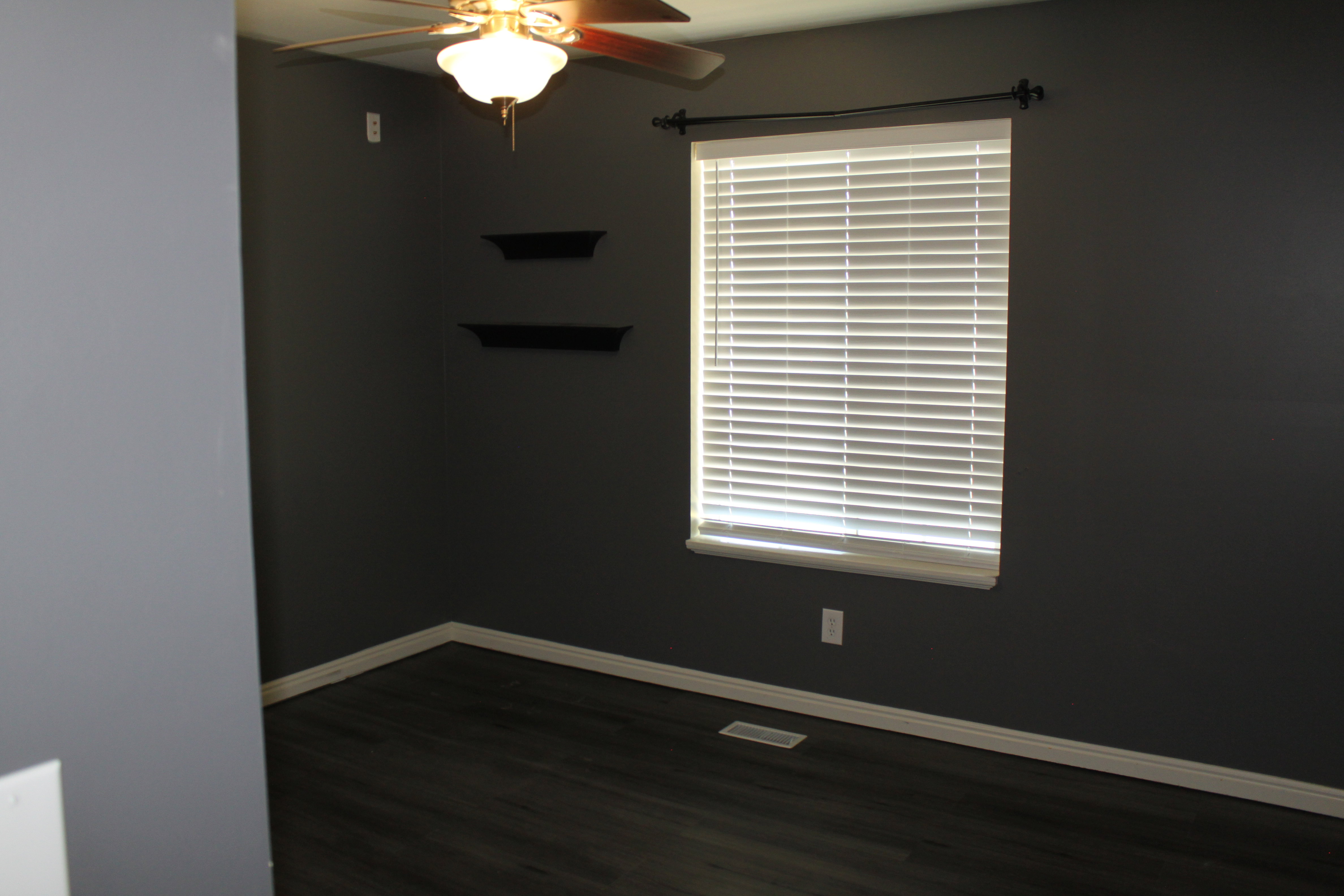 Room with dark gray walls, wood-finish flooring, and white baseboards