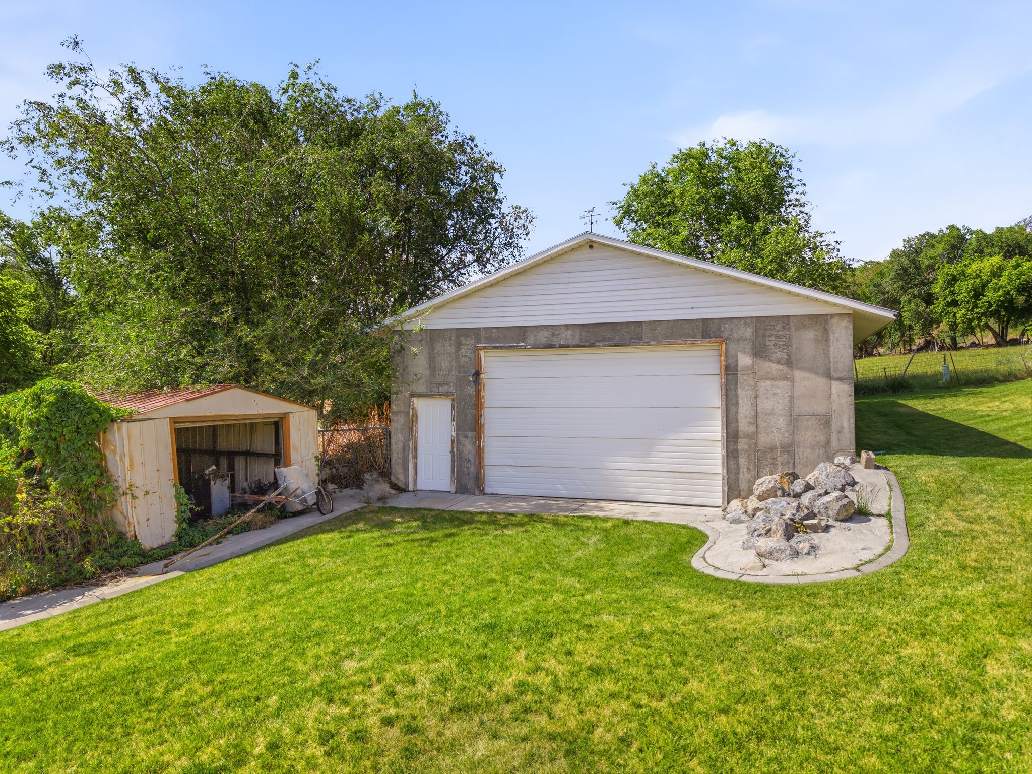 Detached concrete block garage with a white sectional door and a separate entry door