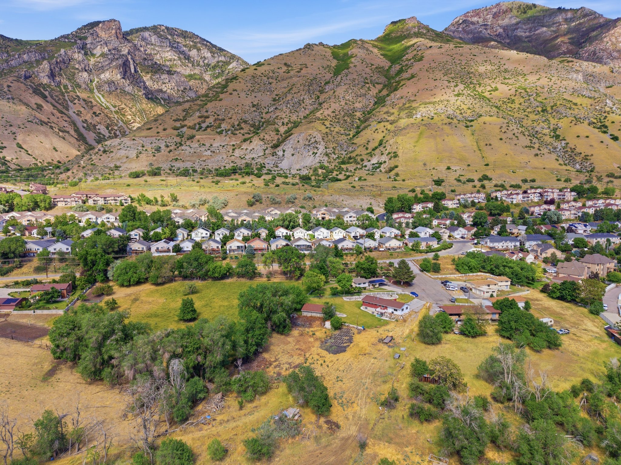 Aerial perspective showcasing a residential community nestled at the base of expansive, natural mountain terrain