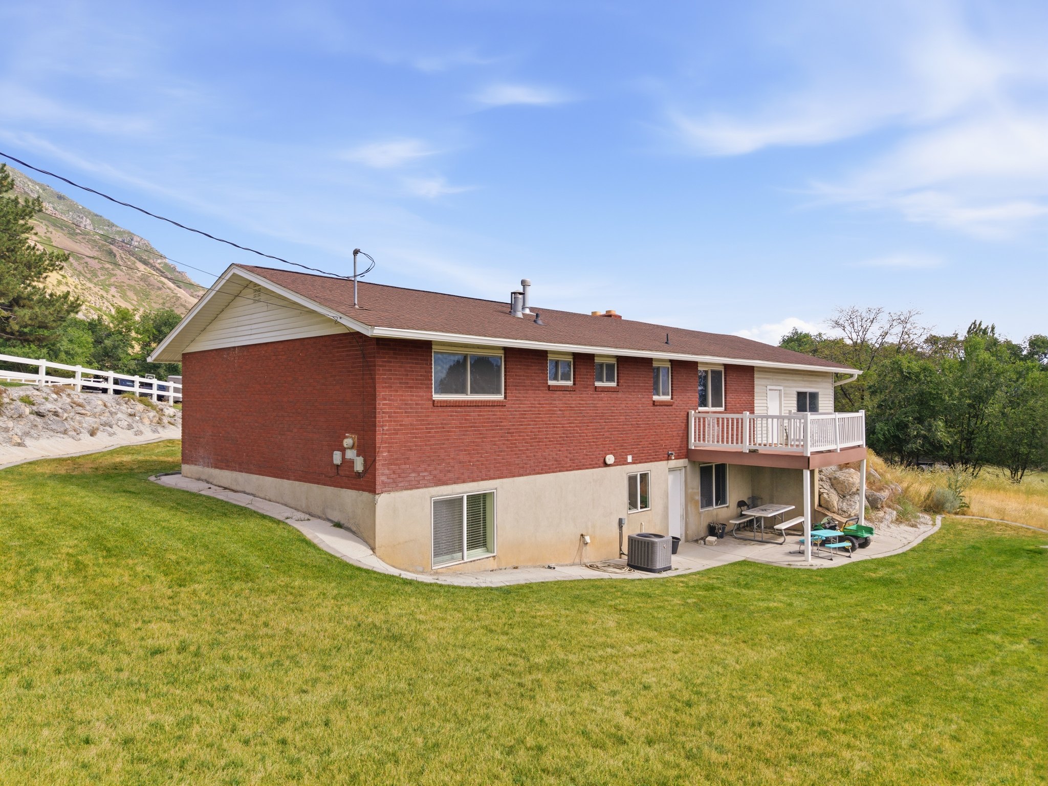 Rear exterior featuring a red brick facade, white siding, and a multi-level deck with white railings