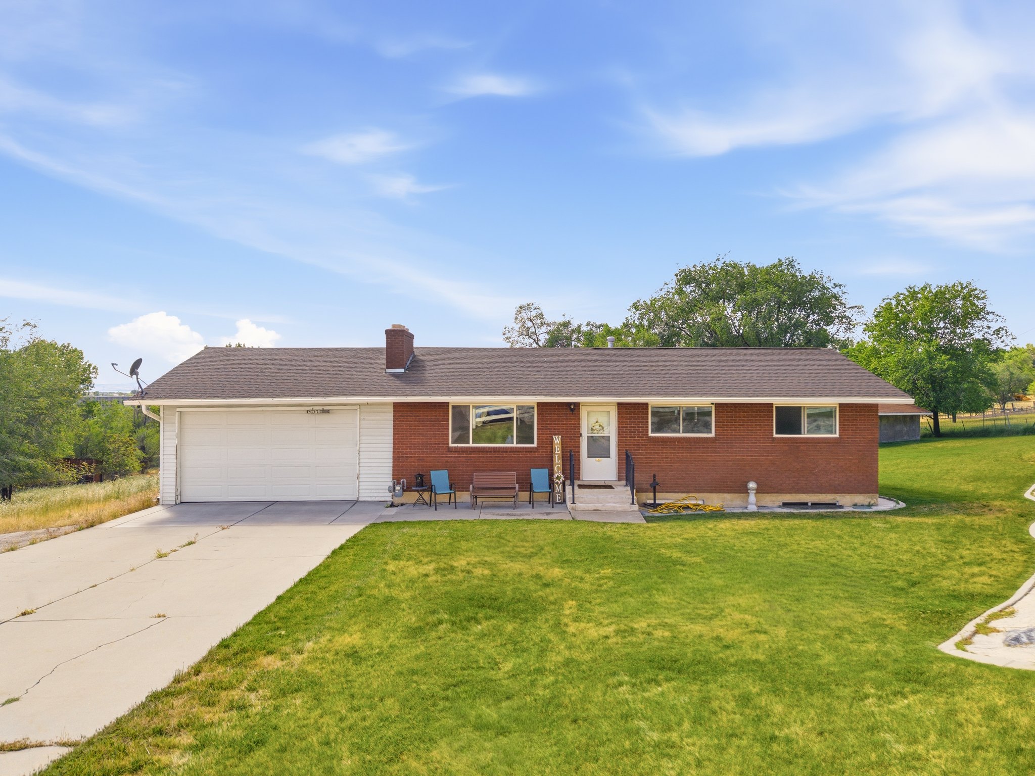 Brick ranch-style residence featuring a two-car garage, concrete driveway, and front lawn