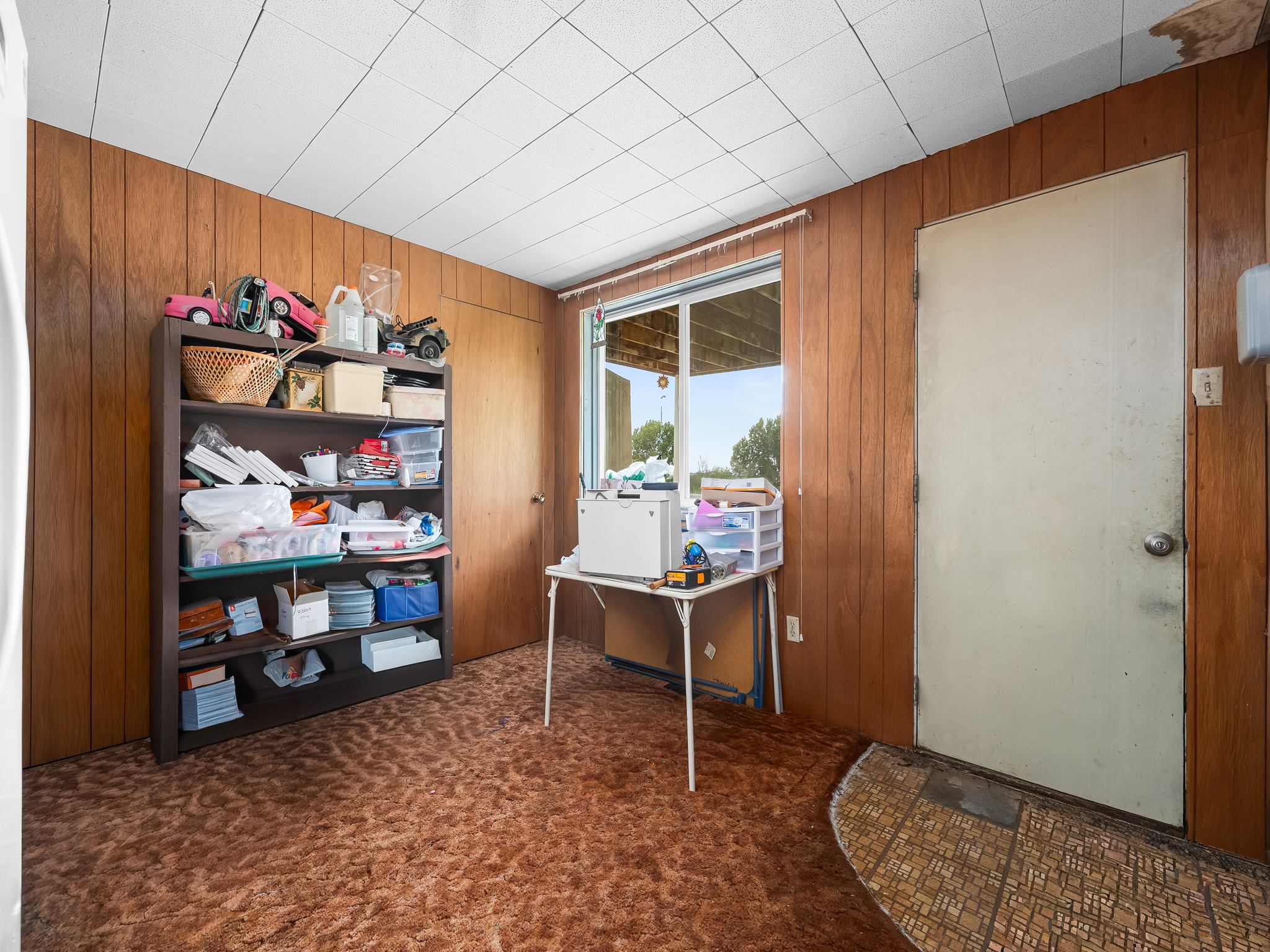 Room featuring wood-paneled walls, a drop ceiling, and patterned carpet flooring