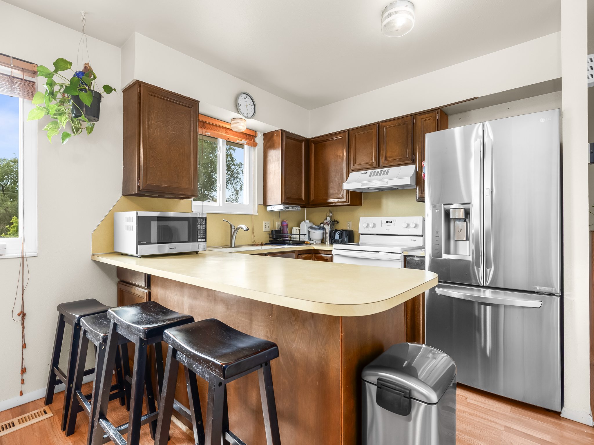 Kitchen featuring a peninsula counter with seating, wood-finish cabinetry, stainless steel refrigerator, and wood-finish flooring