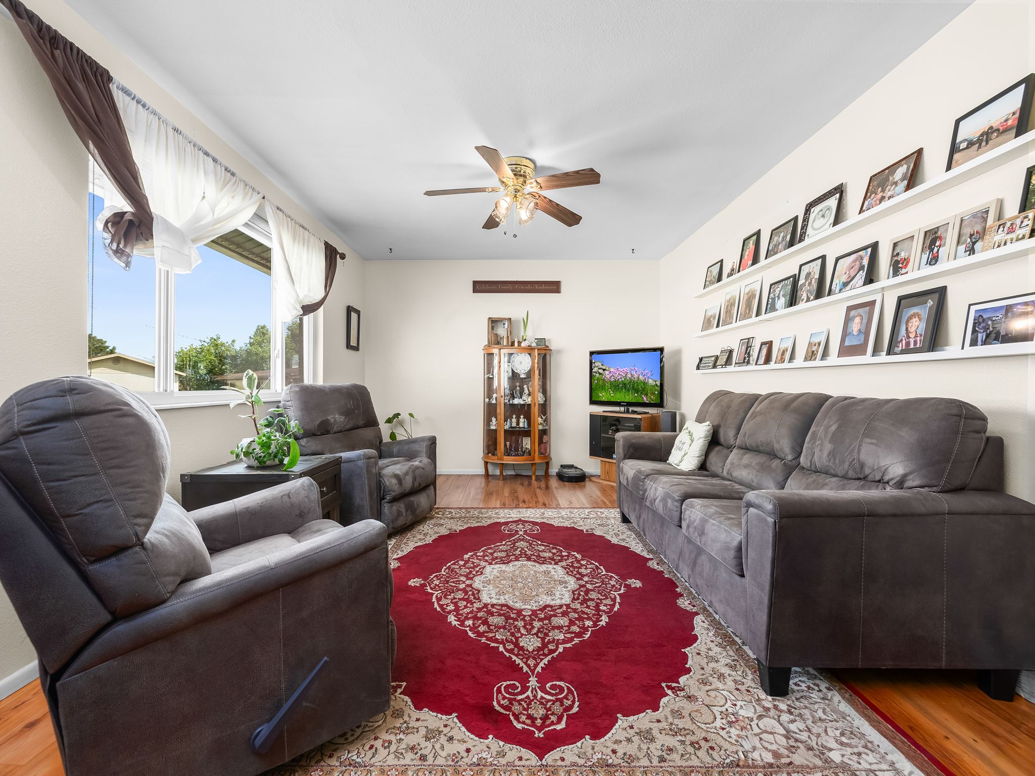 Living room featuring wood-finish flooring, a ceiling fan, and white walls