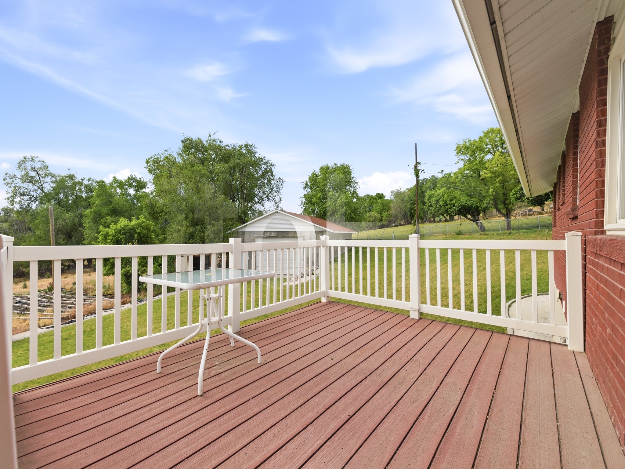 Expansive rear deck featuring wood-finish flooring and a white railing system