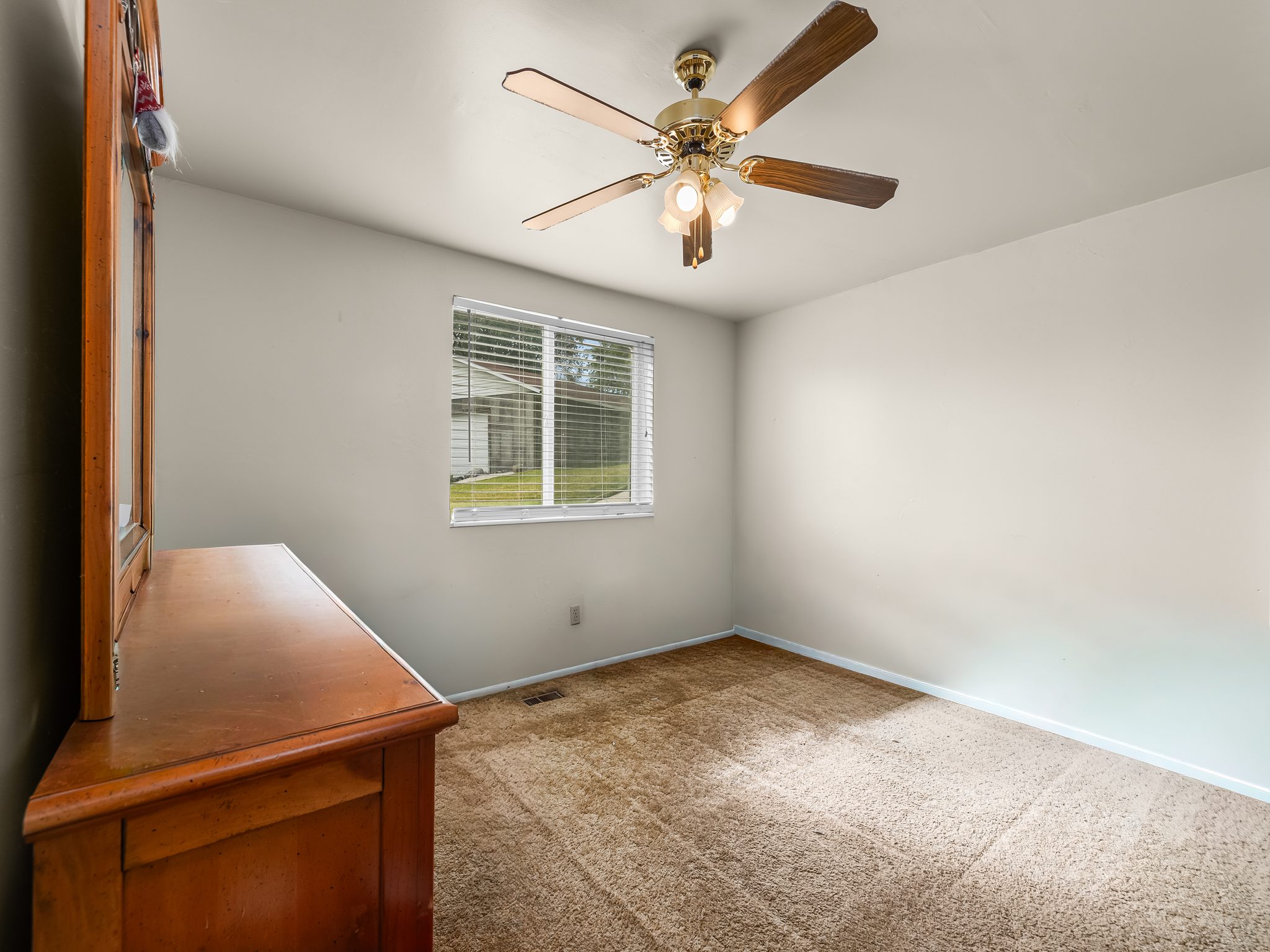 Carpeted room featuring a ceiling fan with integrated lighting, a window with horizontal blinds, and angled ceilings