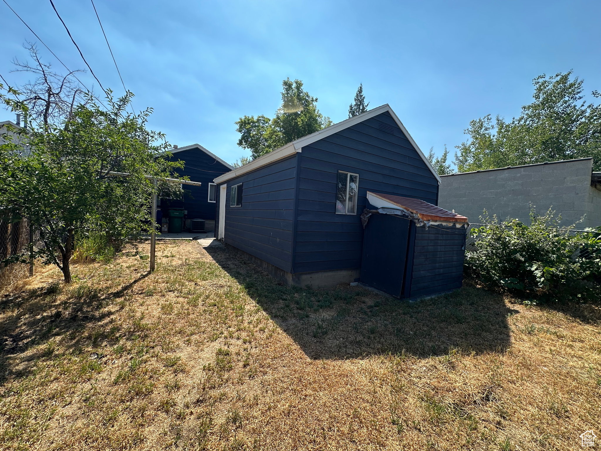 Detached outbuilding with dark blue siding and a white trim roofline