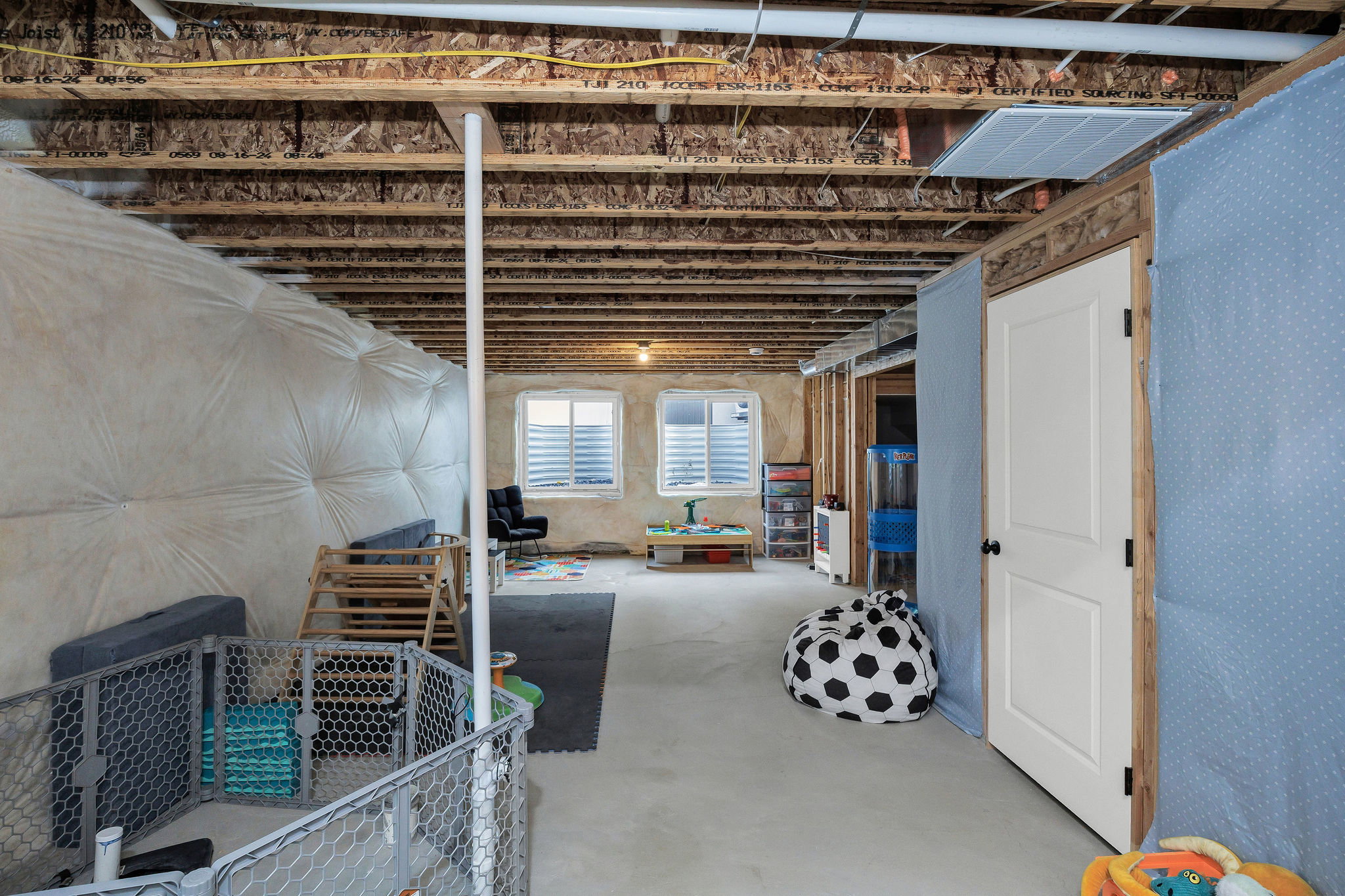 Unfinished lower level featuring an exposed ceiling, concrete flooring, and multiple windows with plantation shutters