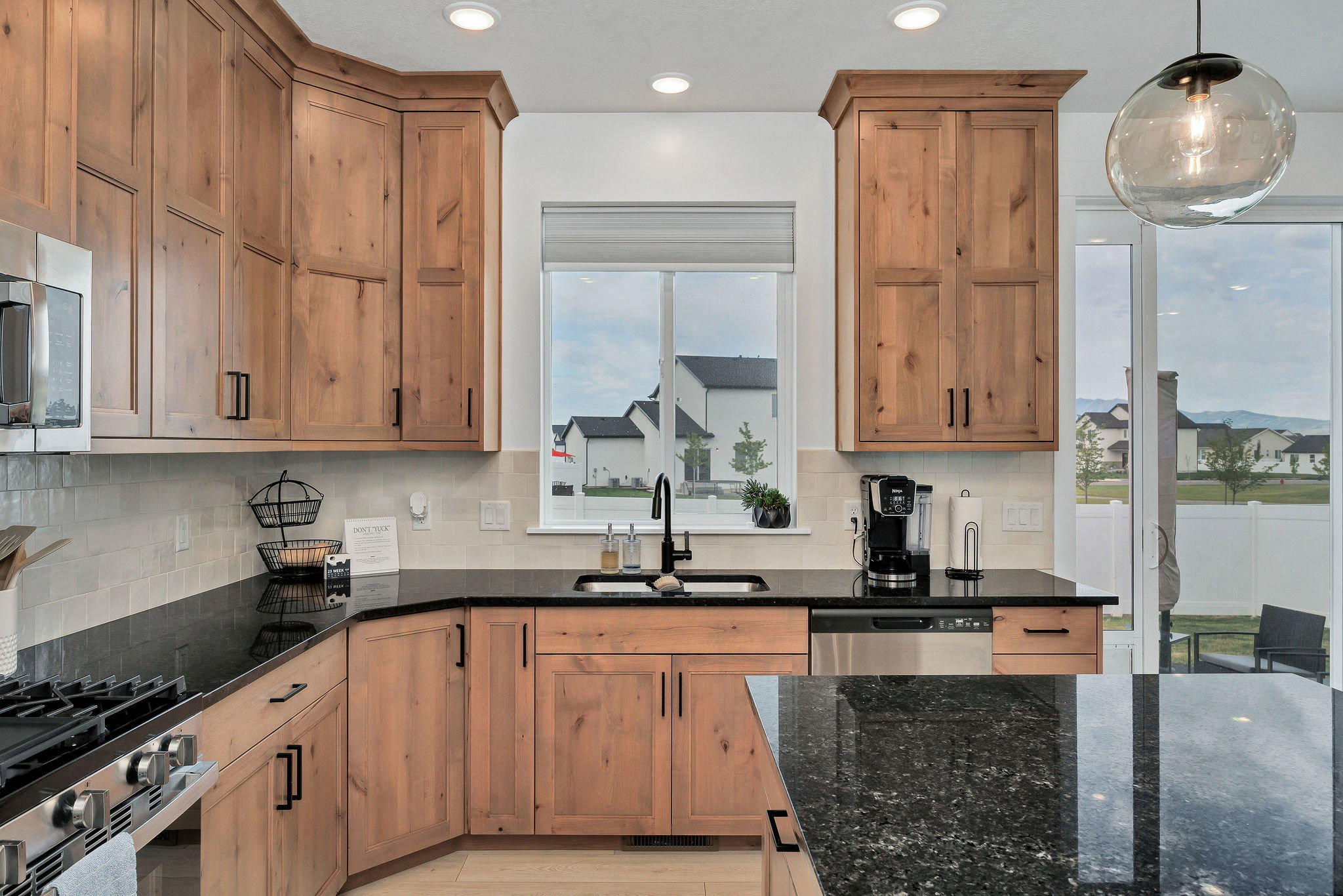Kitchen featuring warm wood cabinetry, dark countertops, and a full tile backsplash