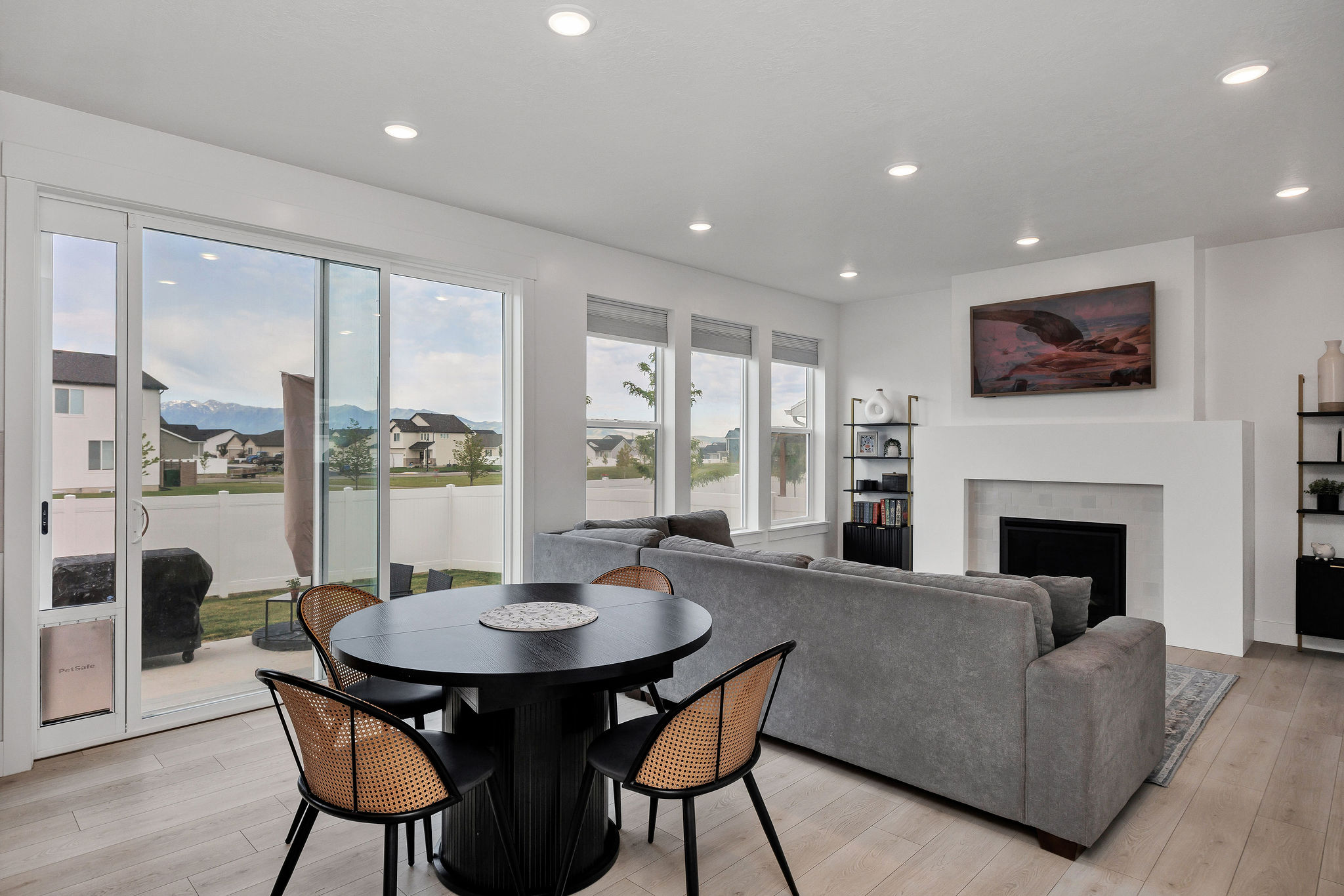 Open-concept living space featuring wood-finish flooring, a contemporary fireplace with a clean-lined mantel, recessed ceiling lighting, and large windows with mountain scenery