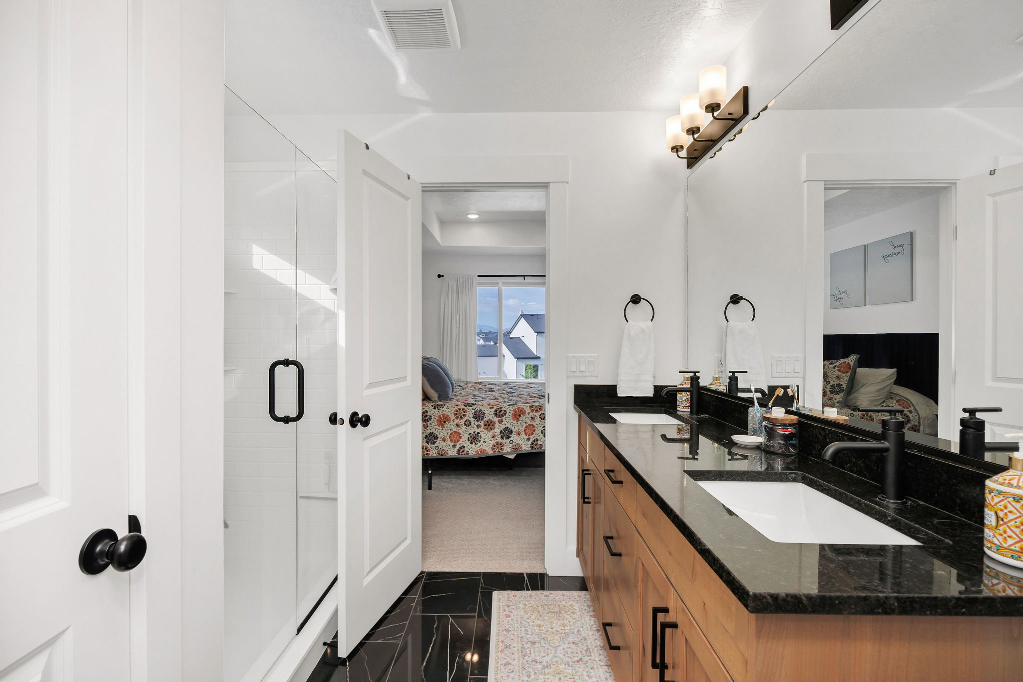 Bathroom featuring a dual vanity with black countertops, integrated sinks, and matte black fixtures