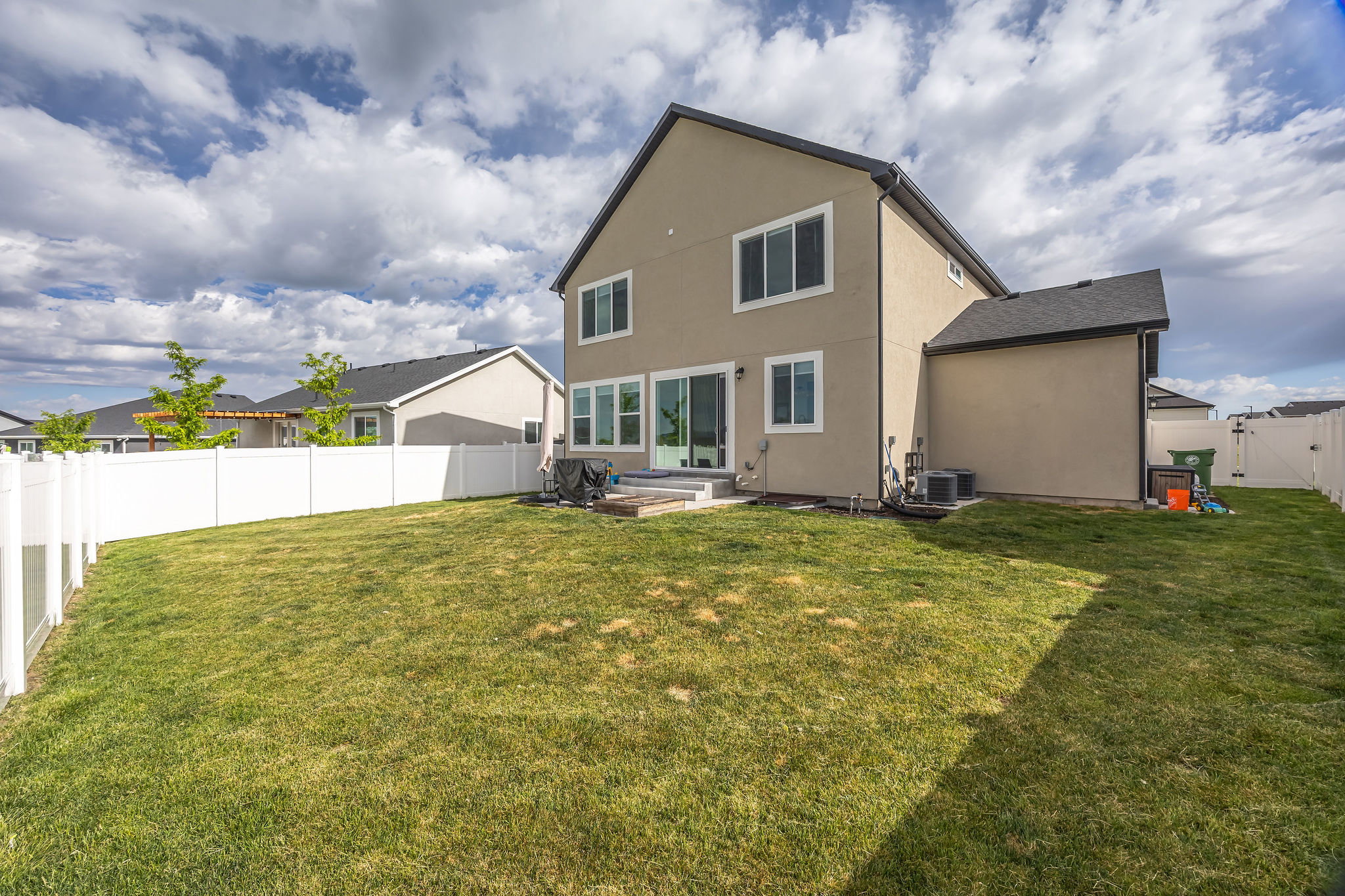 Spacious backyard featuring a manicured lawn and complete white vinyl fencing
