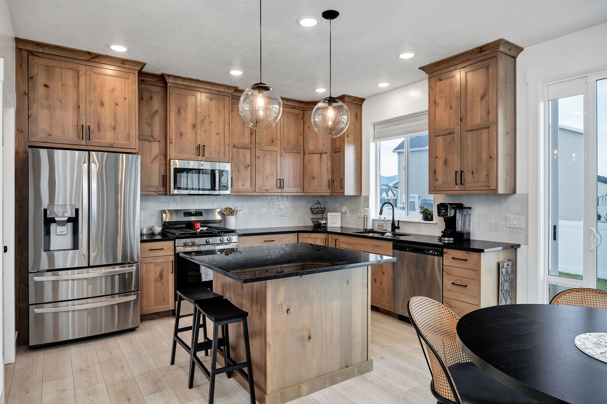 Kitchen featuring wood-finish cabinetry, stainless steel appliances, black countertops, a central island with bar seating, and wood-finish flooring