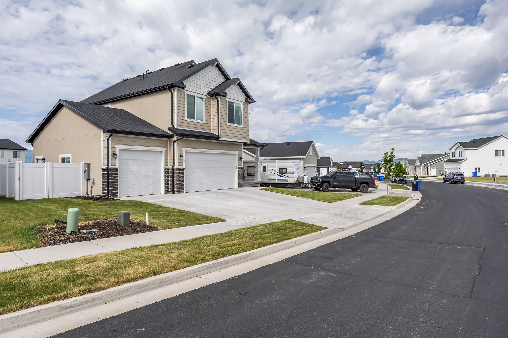 Modern two-story residence featuring a two-car garage, partial stone veneer accents, and a contrasting neutral-toned exterior