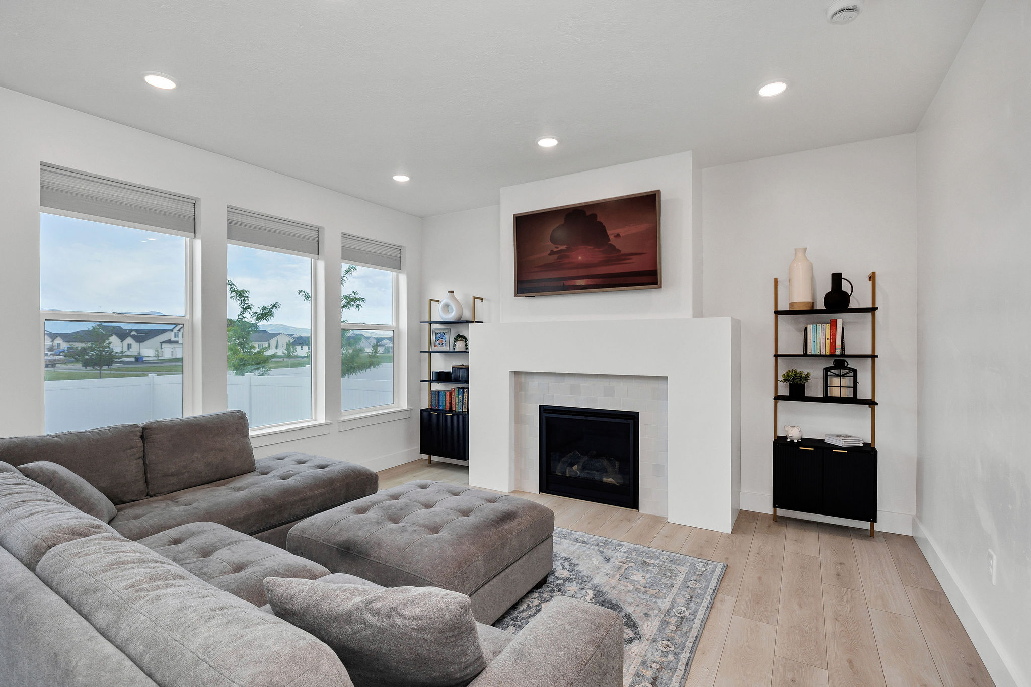 Bright living area featuring wood-finish flooring, a contemporary fireplace with a tiled surround, recessed lighting, and a prominent built-in mantel