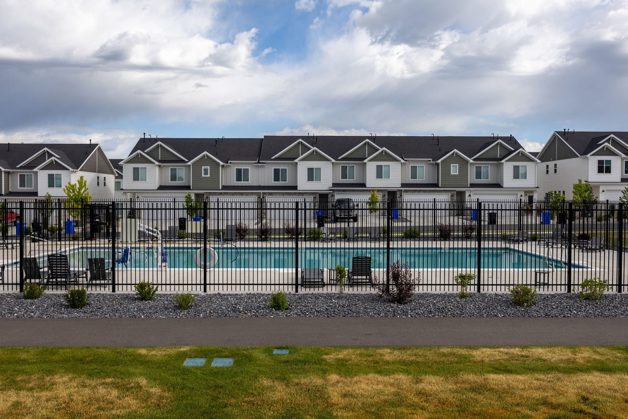 Community swimming pool featuring a black perimeter fence and surrounding lounge seating