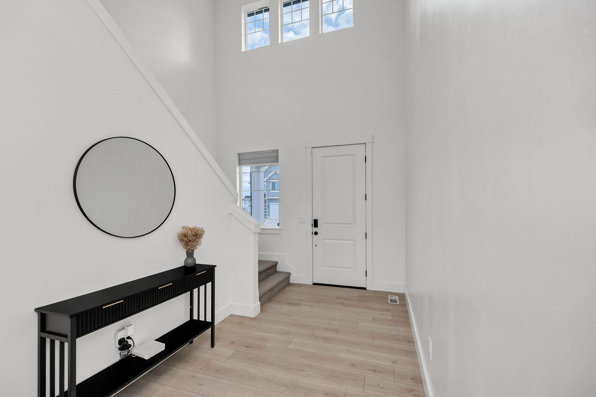 Bright entryway with wood-finish flooring and a high ceiling