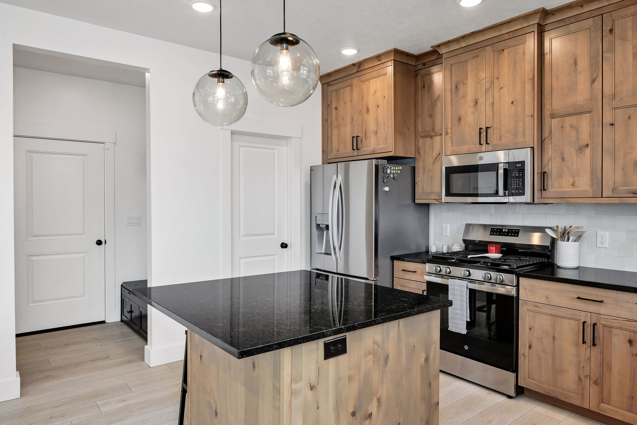 Kitchen featuring a central island with a dark countertop, light wood-finish cabinetry, stainless steel appliances, and a white subway tile backsplash