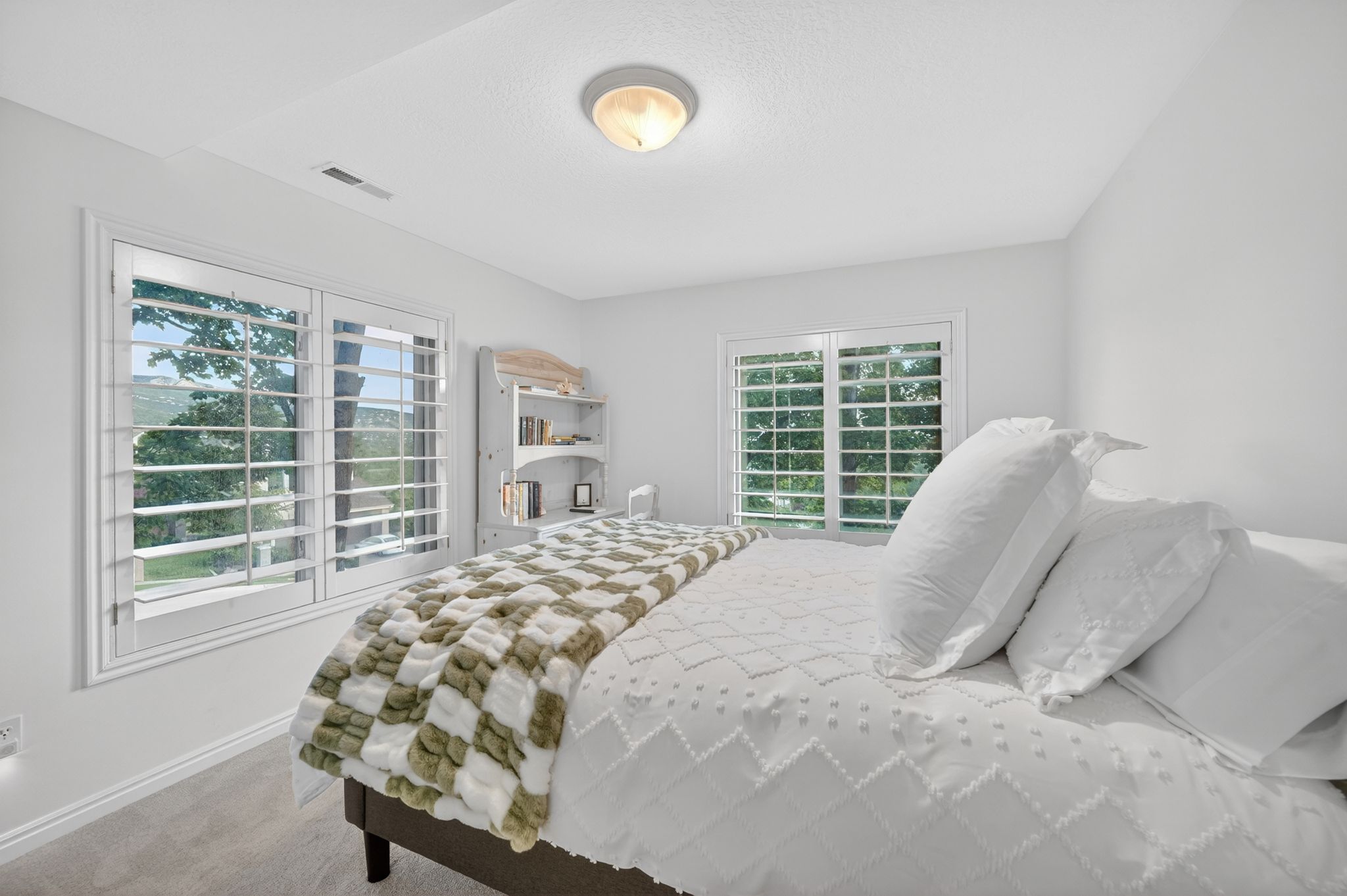Bright room featuring two windows with white plantation shutters